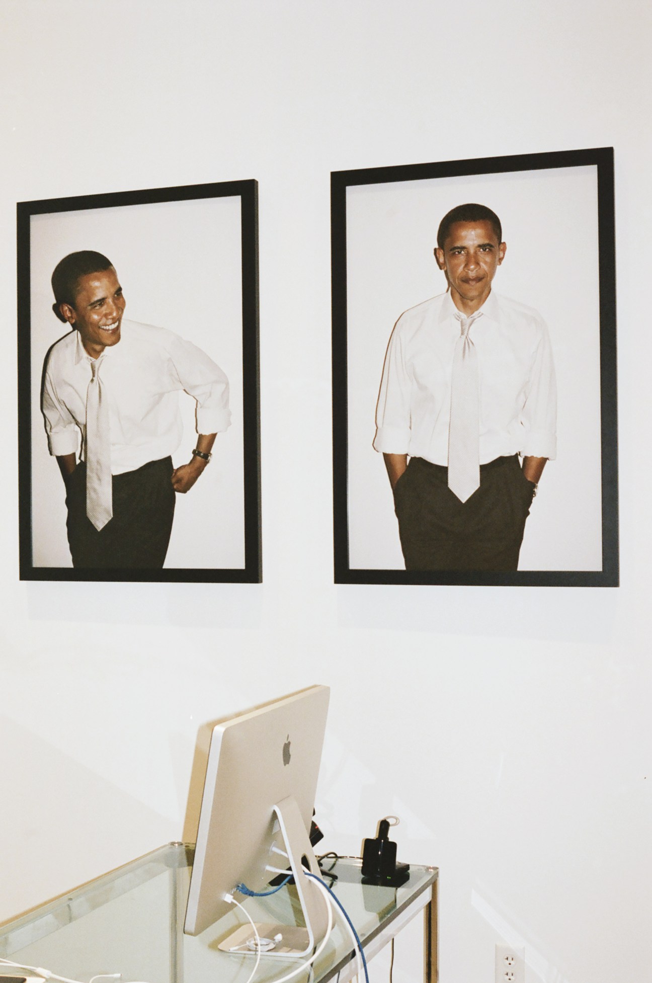 Two framed portrait photographs of Barack Obama by Terry Richardson displayed on an office wall above a desk with computer.