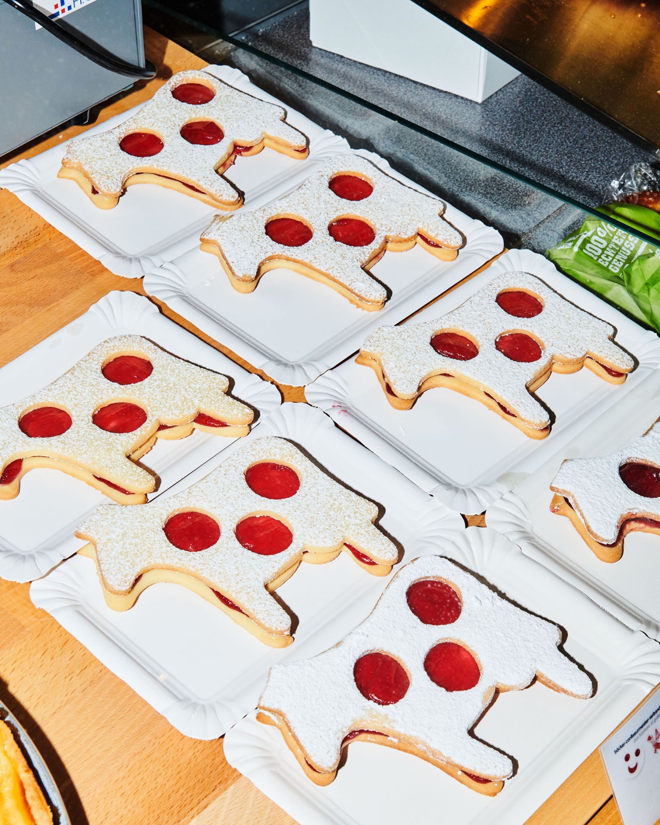 Cow-shaped cookies with red jam filling displayed on white plates at Olma fair.