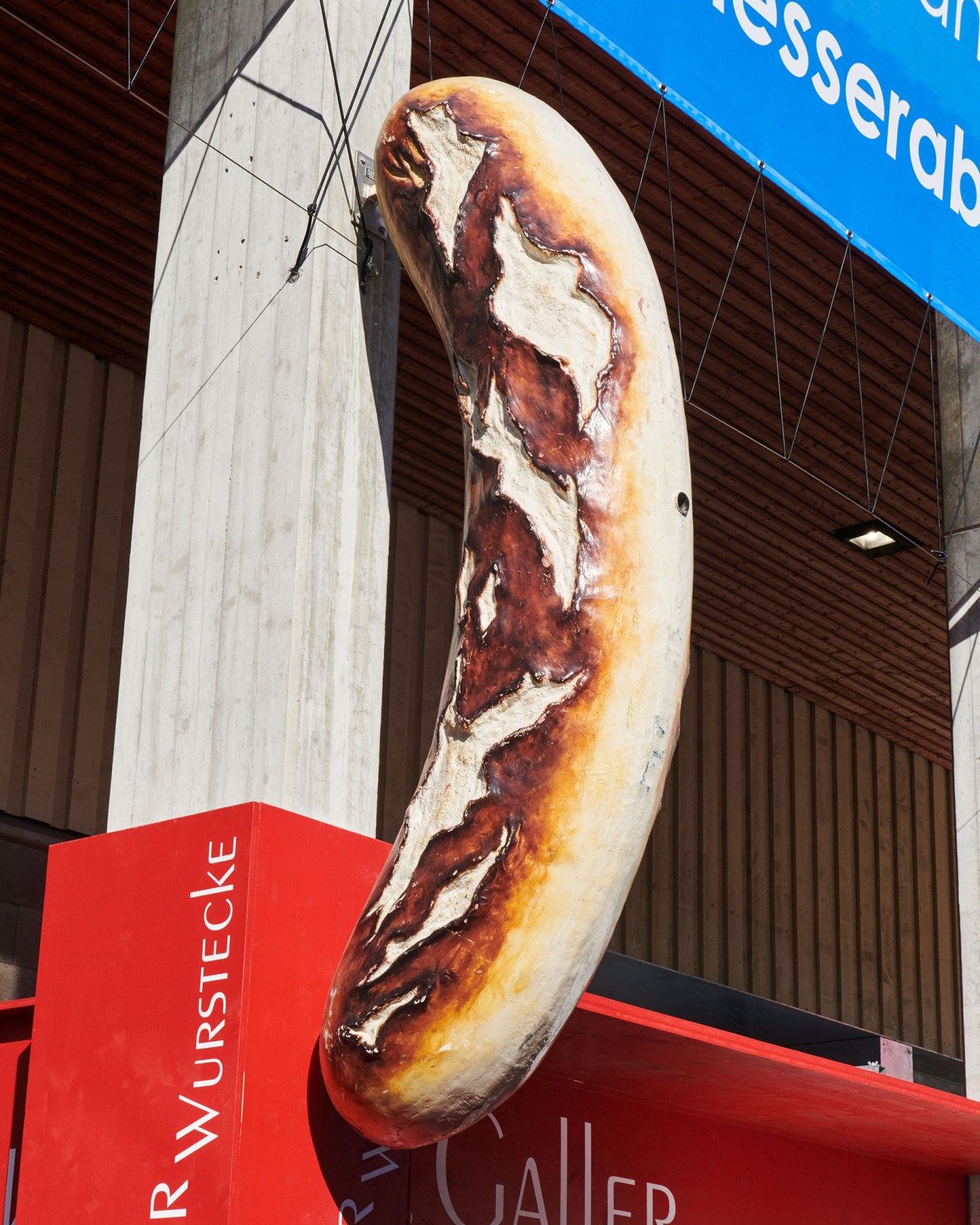 Giant sculptural bratwurst on display at Olma fair with red signage below