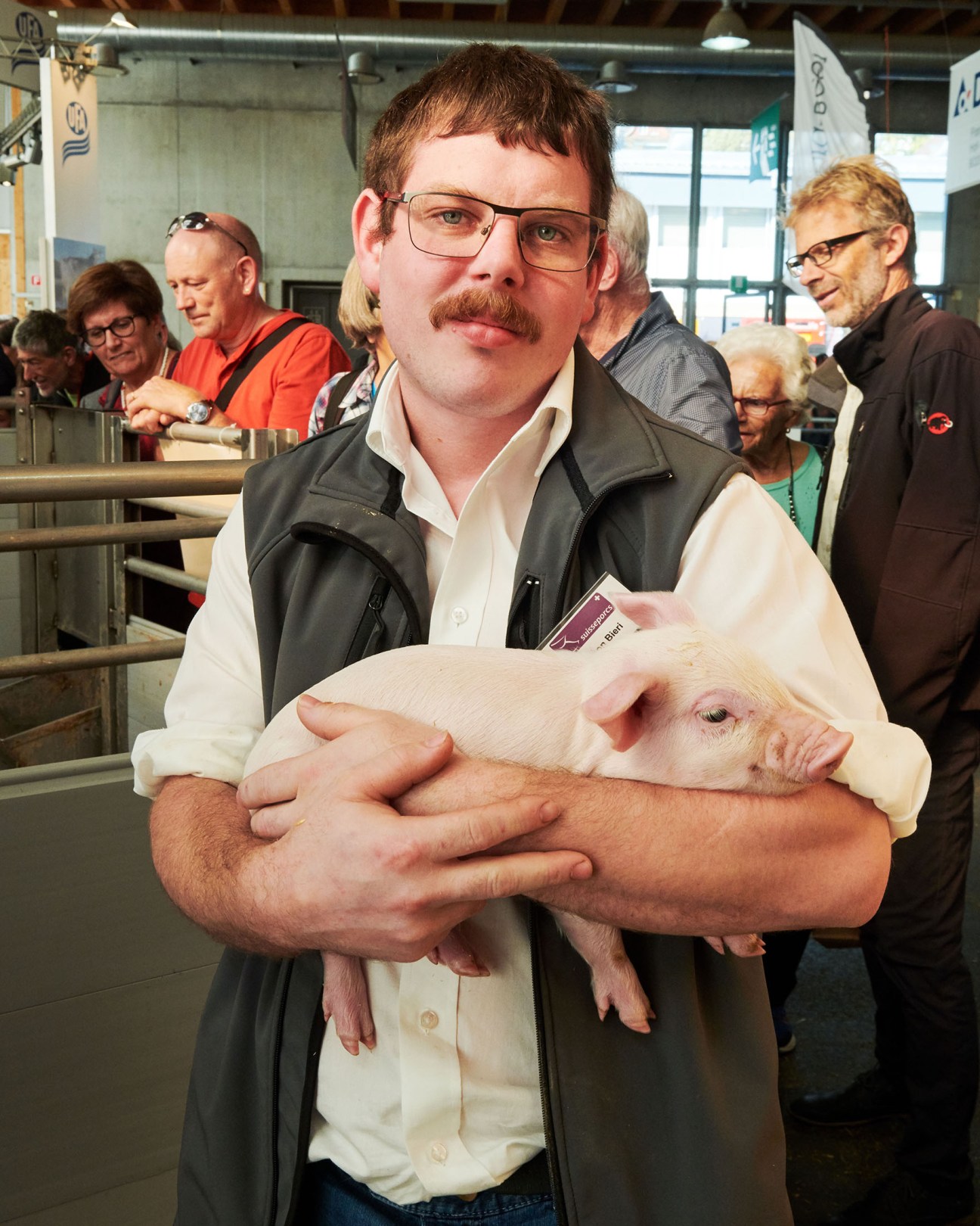 Simon Bieri from Suisseporcs holding a young piglet at the Olma fair.