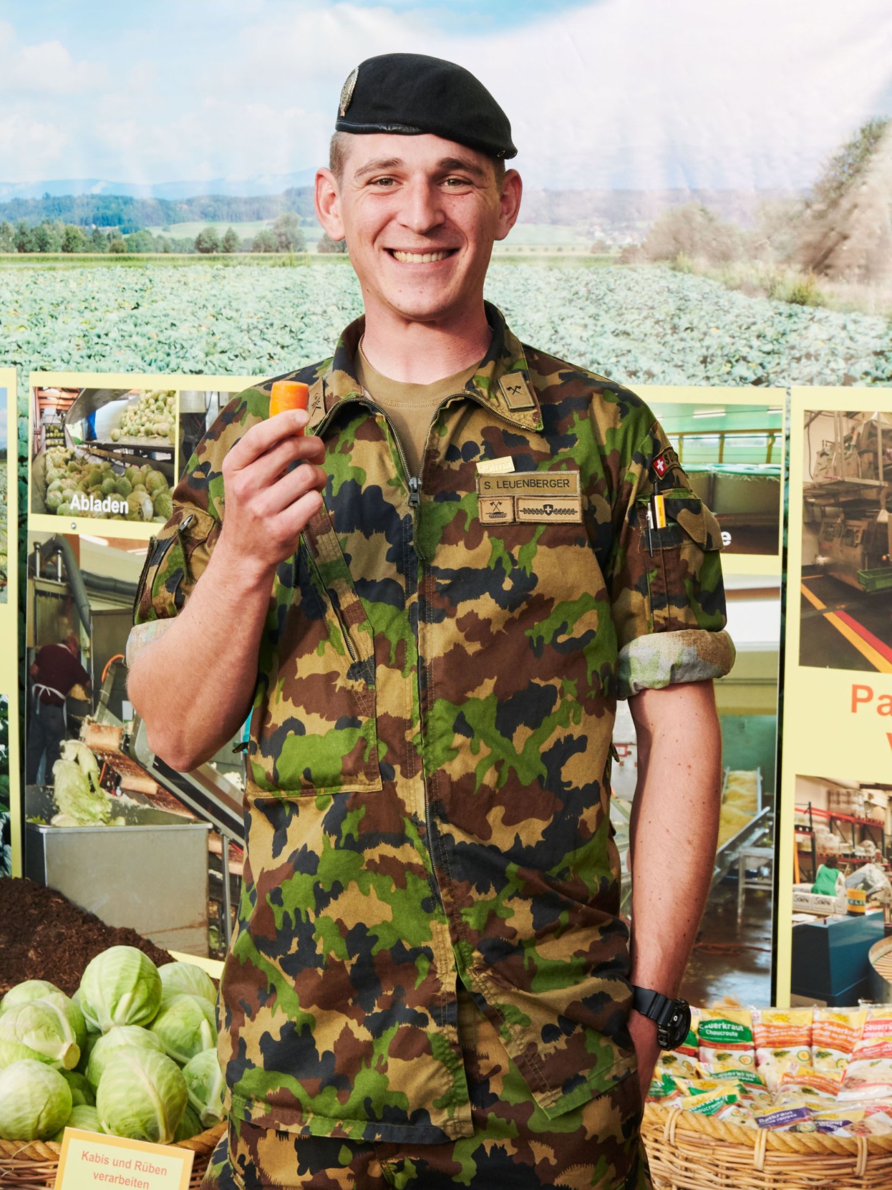 Swiss army soldier Sebastian Leuenberger in camouflage uniform holding an orange vegetable at Olma agriculture fair.