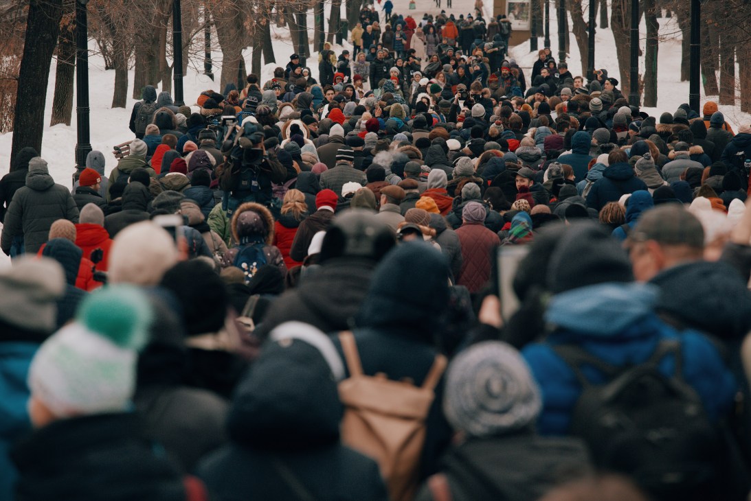 Large crowd of protesters gathered in a snowy Moscow boulevard lined with bare trees wearing winter clothing.