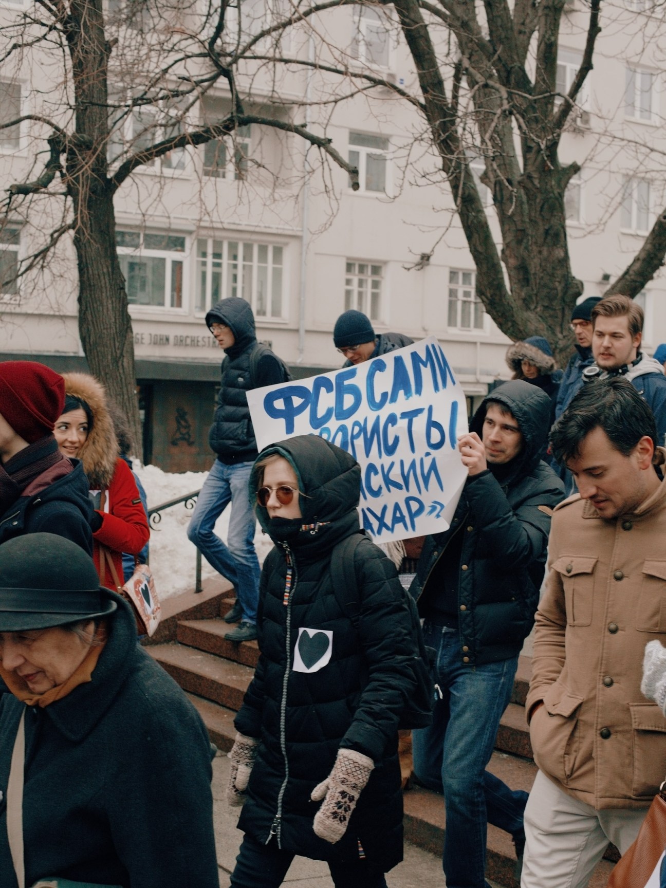 Russian pro-democracy activists and protesters gathered on a street holding signs with Cyrillic text during a demonstration.