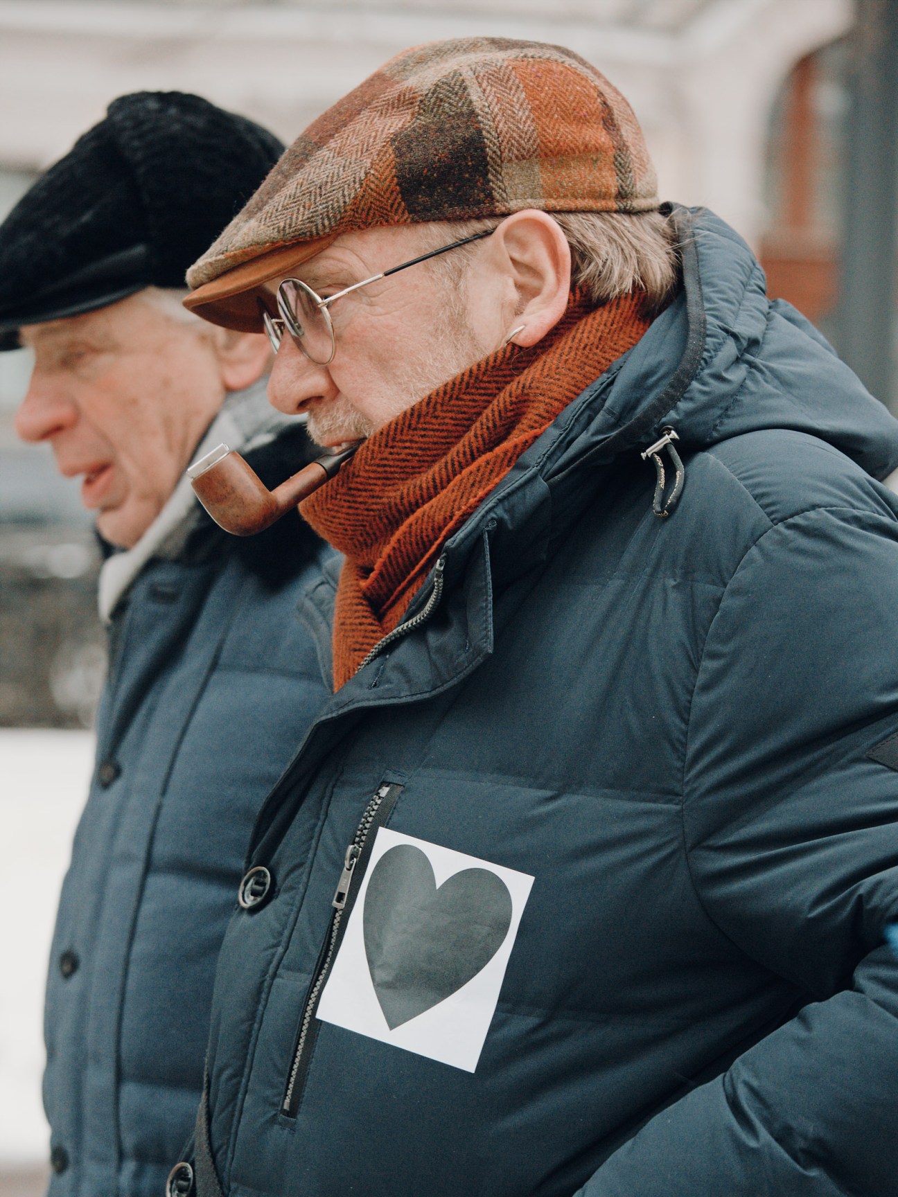 An elderly man wearing a black heart symbol on his jacket marches in solidarity with Anastasia Shevchenko.