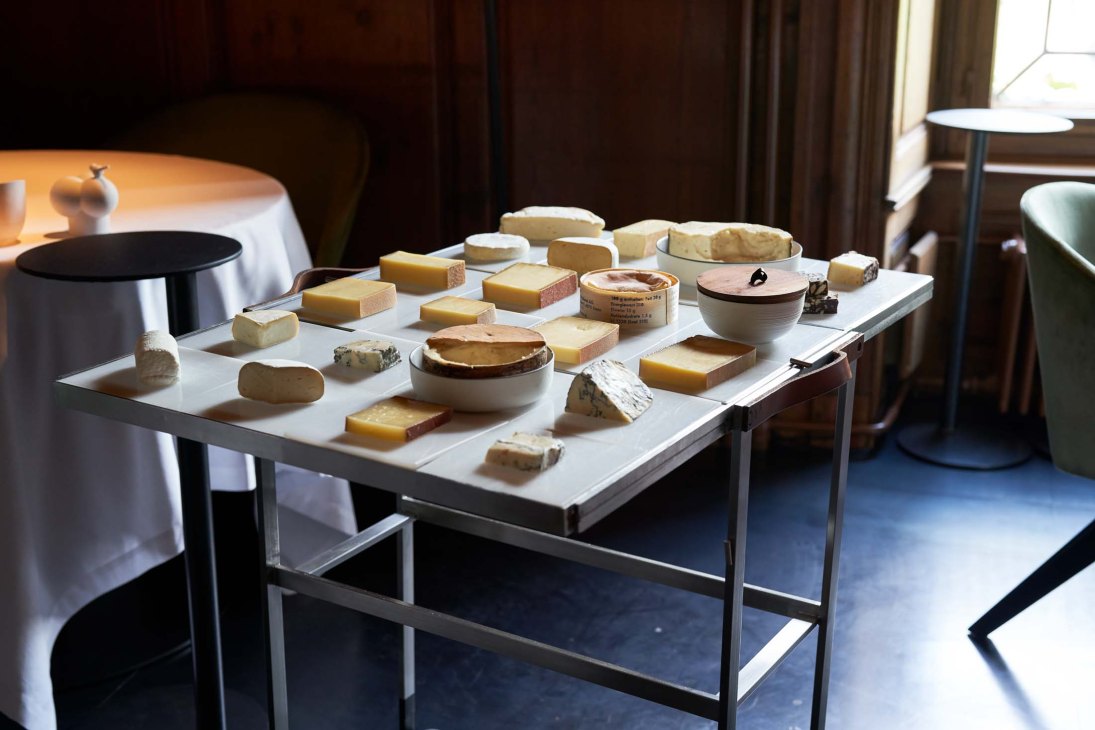 An artisanal selection of Swiss Alpine cheeses displayed on a white table in an elegant dining room setting
