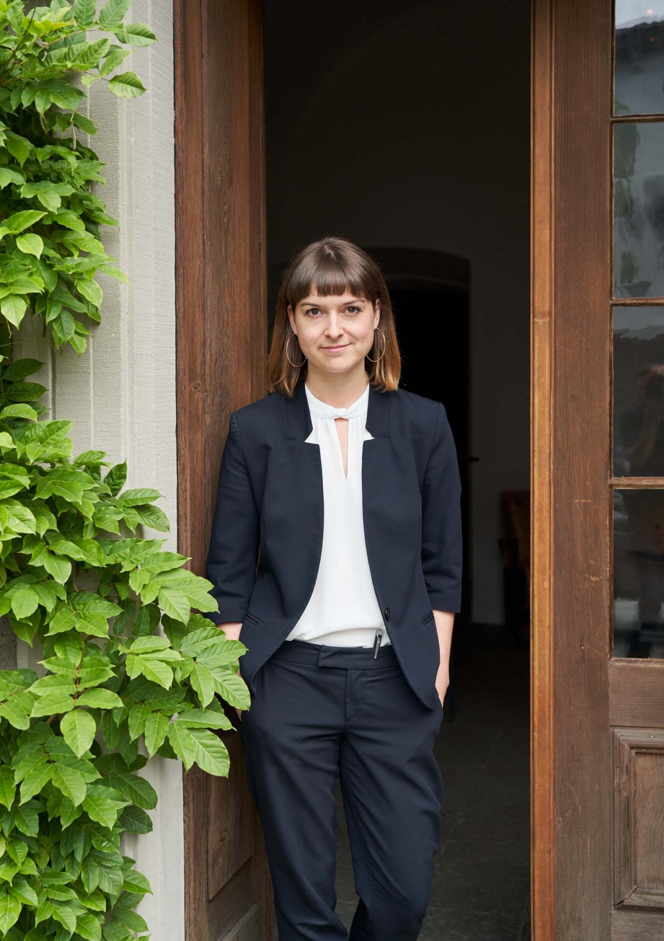 Restaurant manager Anna-Lena Junge standing in a doorway wearing a dark blazer and white shirt