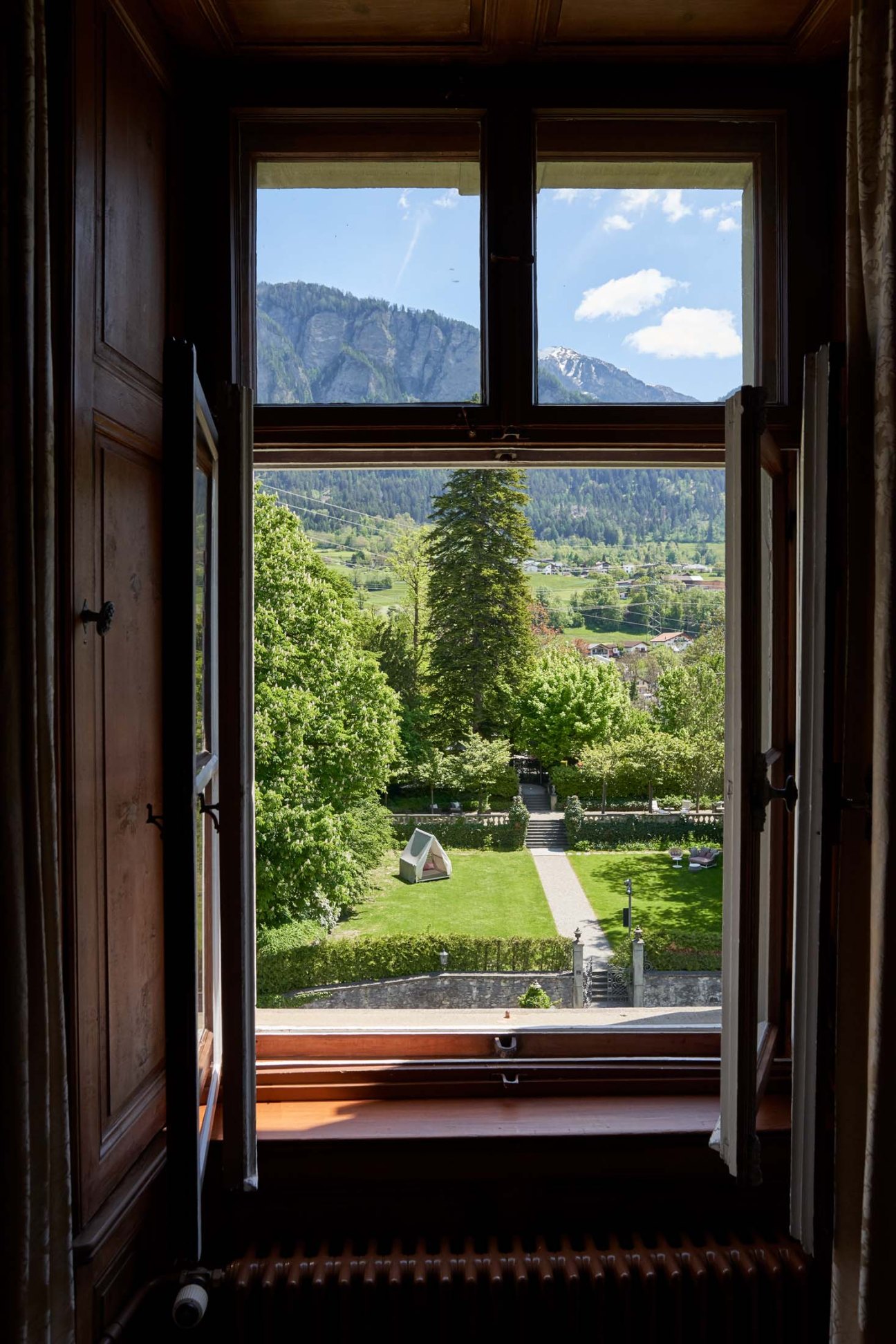 Swiss Alpine landscape view through open wooden doors from a hotel suite window