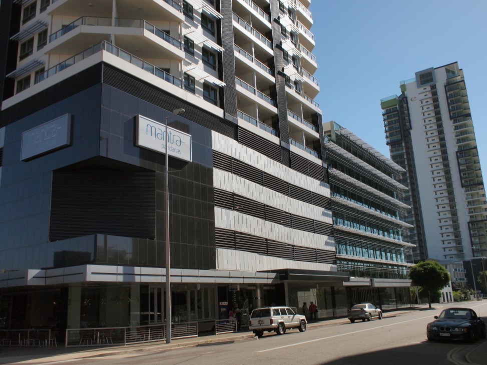 Modern multi-story residential and commercial buildings in Darwin's central business district under clear blue sky.
