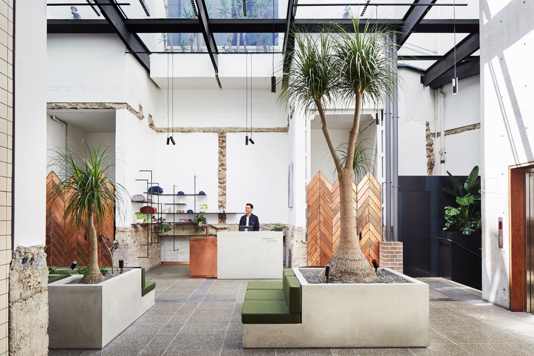 Paramount House Hotel lobby with palm trees, exposed brick walls, skylight, and reception desk.