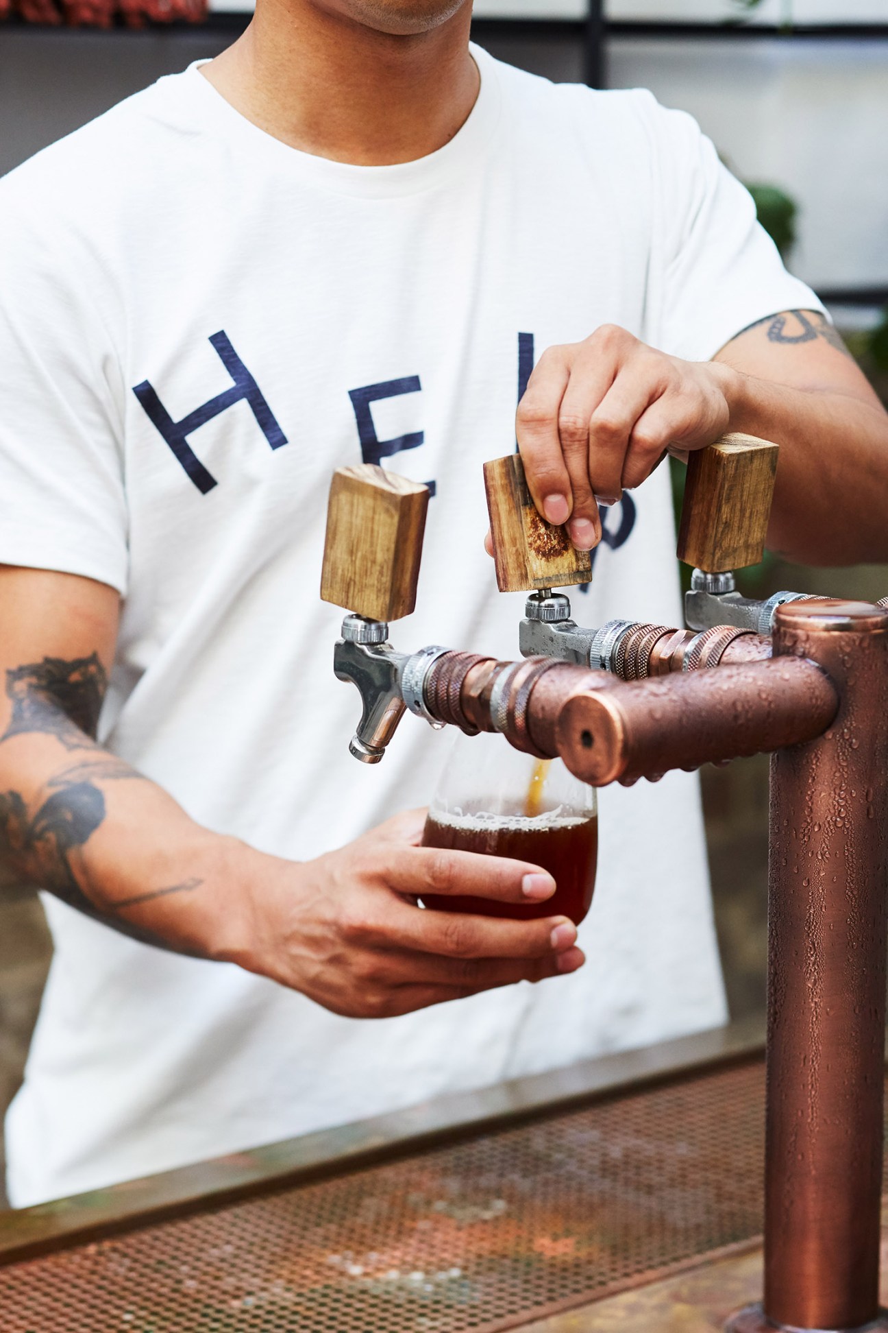 Bartender pouring craft beer from wooden-handled tap at Paramount House Hotel bar.