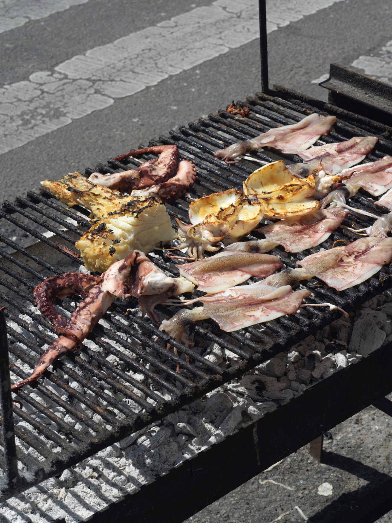 Grilled squid and fish cooking on a charcoal grill at O Tito restaurant in Portugal.
