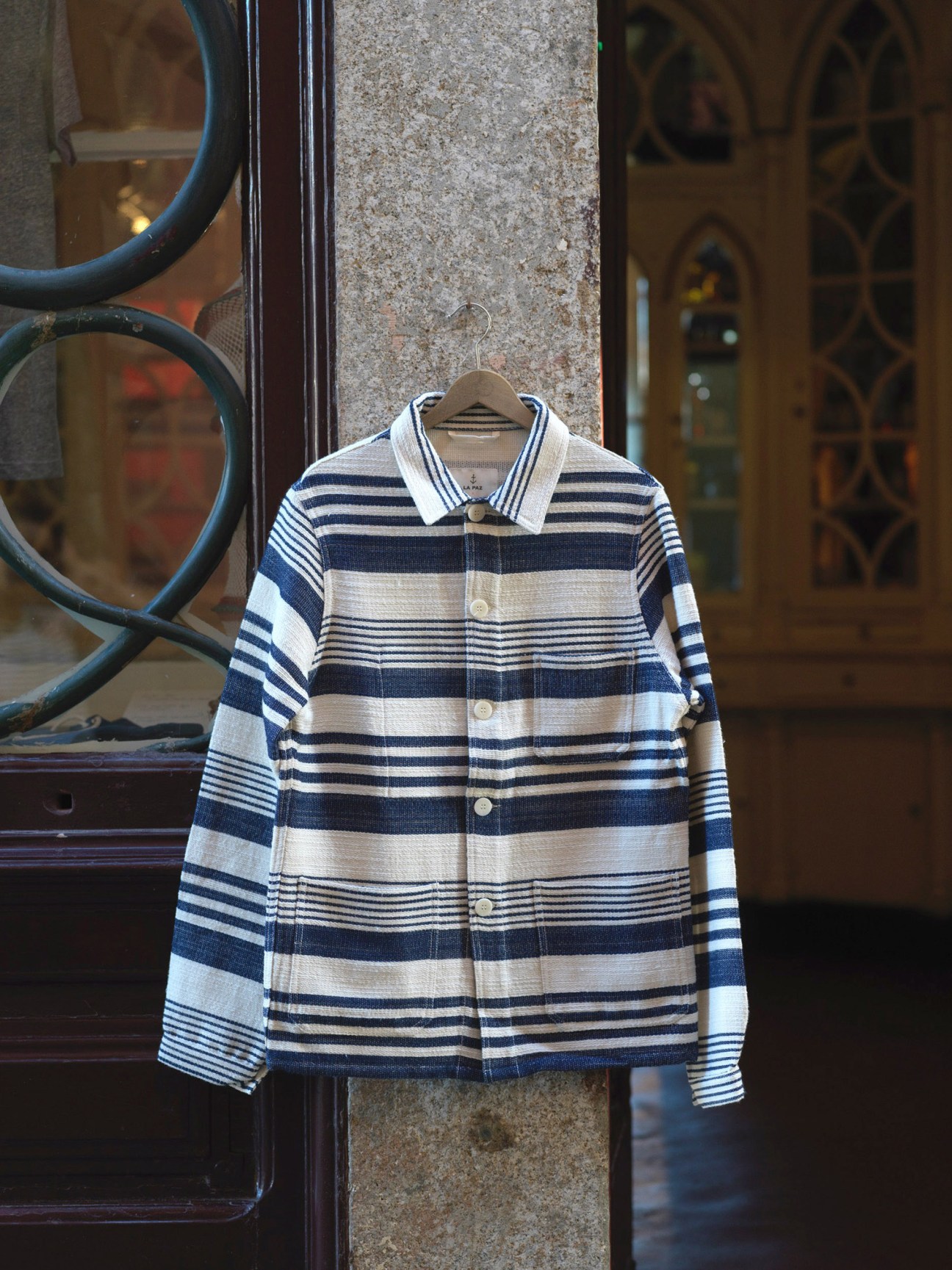 Striped button-up shirt displayed on wooden hanger in La Paz store window.