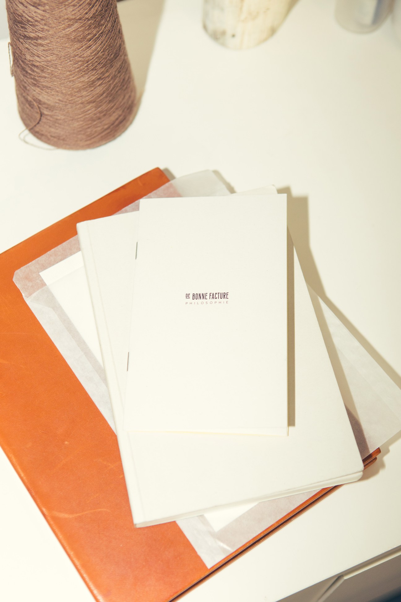 DBF lookbook pages stacked with orange envelopes and brown yarn spool in background