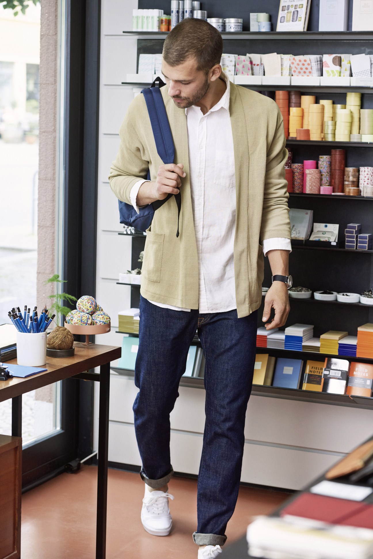 Man in beige cardigan and jeans browses stationery supplies at Luiban shop in Berlin.