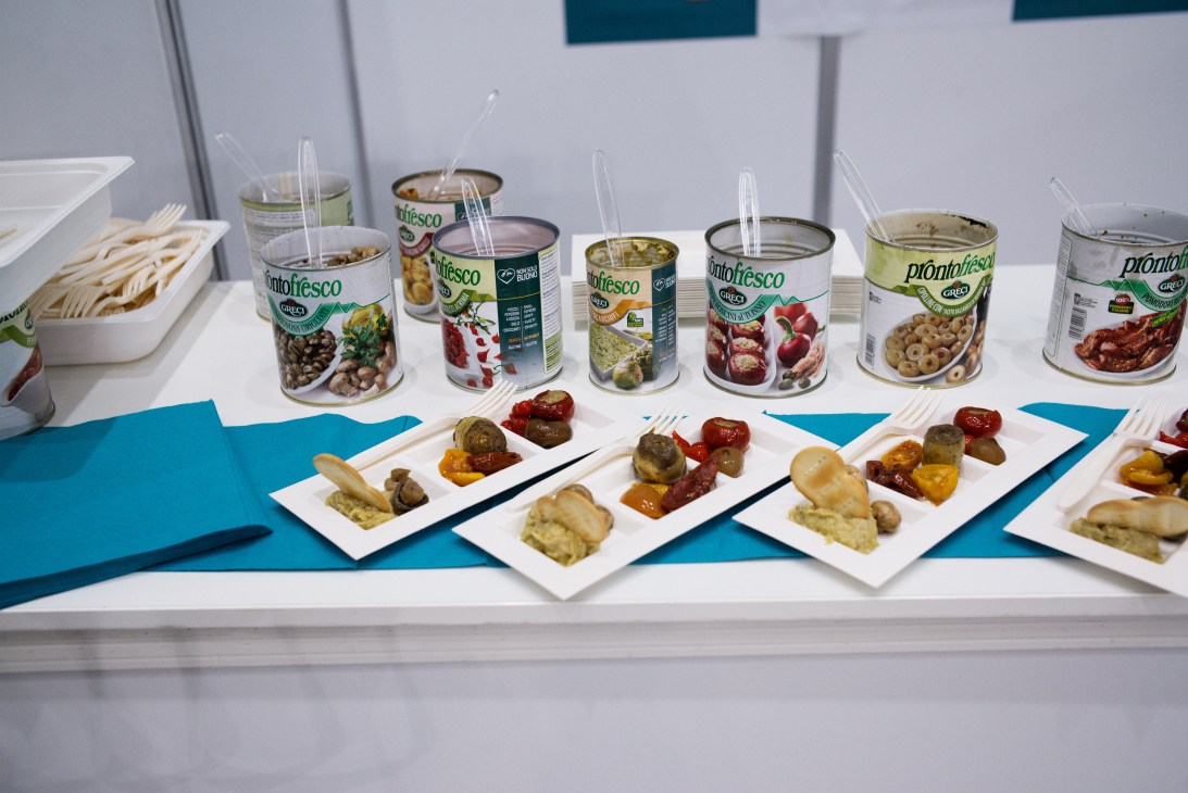 Canned antipasti products and food samples displayed at an aircraft interiors expo booth.