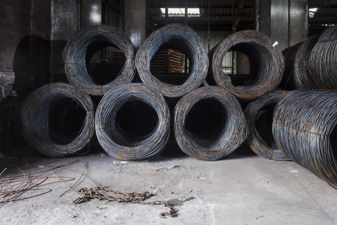 Coils of steel wire bundled and stacked in the factory warehouse for nail manufacturing.