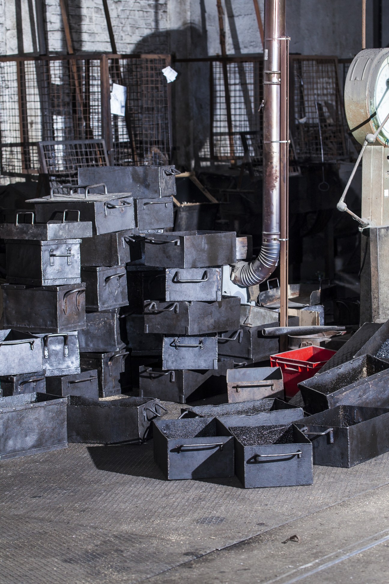 Stacked metal boxes of various sizes at Rivierre nail factory with industrial machinery in the background.