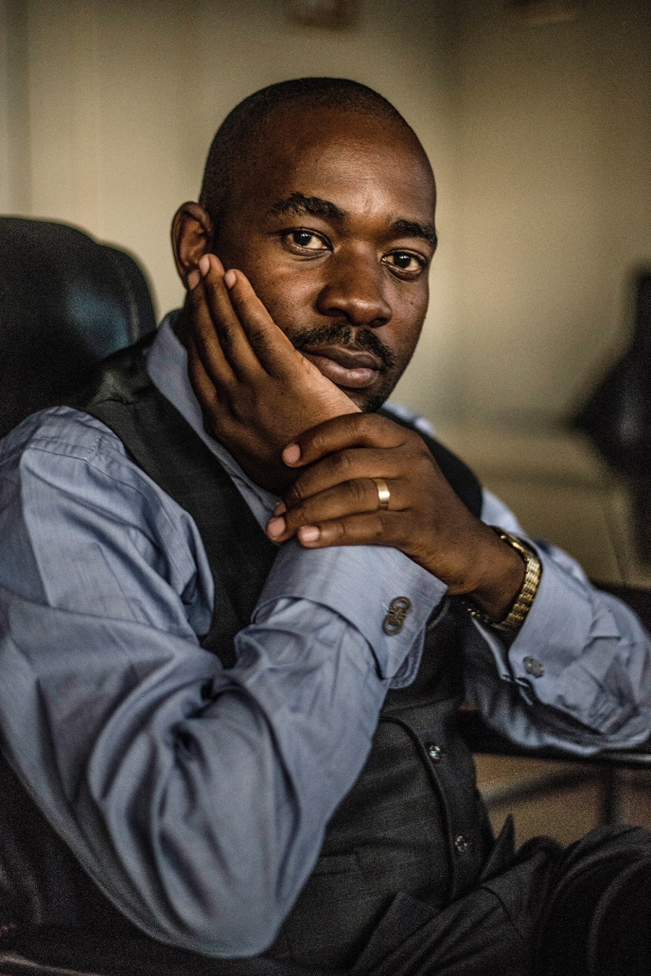 Opposition leader Nelson Chamisa poses for a portrait in his office, hand to his face.