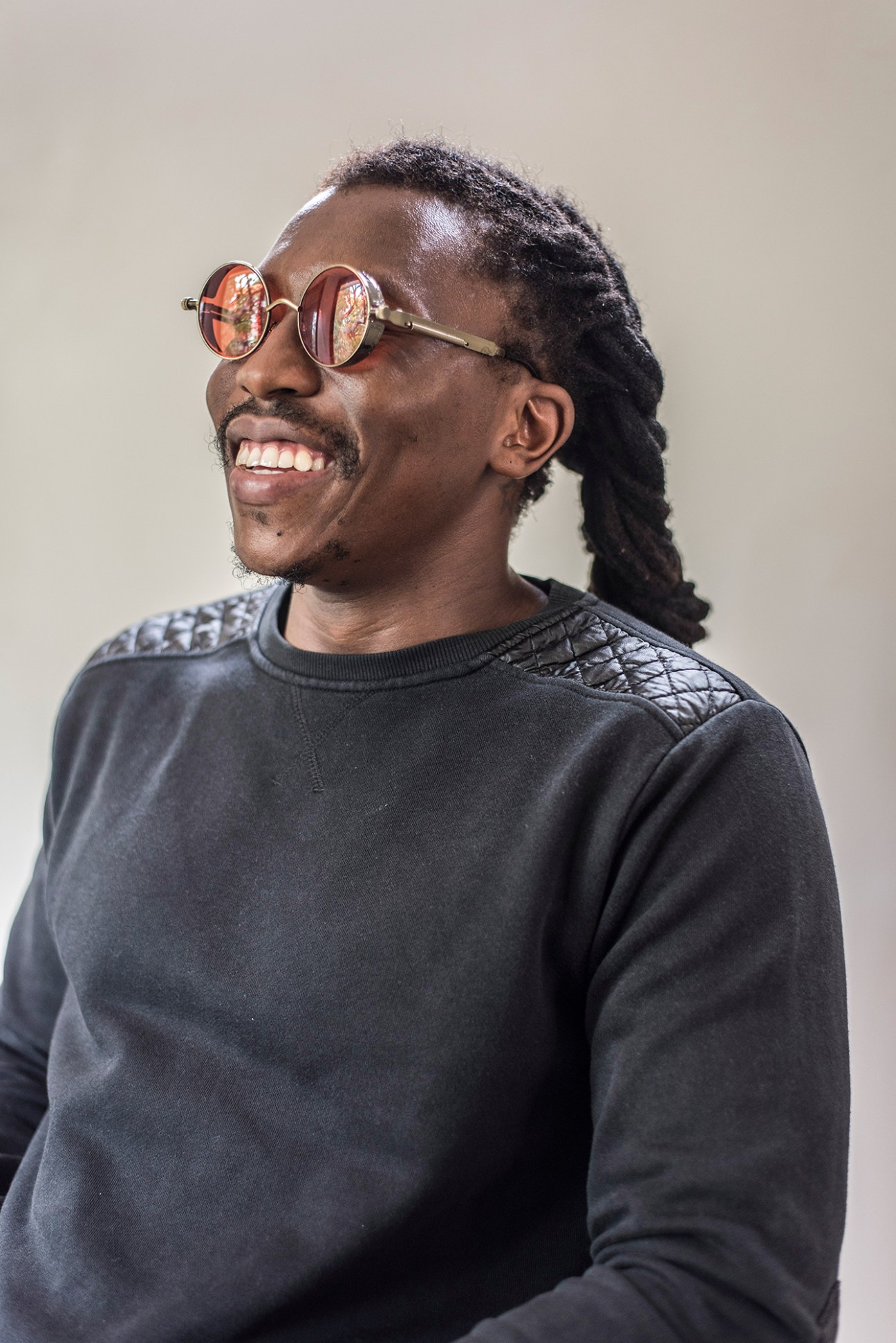 Comedian and spoken-word artist Tongai Makawa wearing round sunglasses and a dark sweatshirt.
