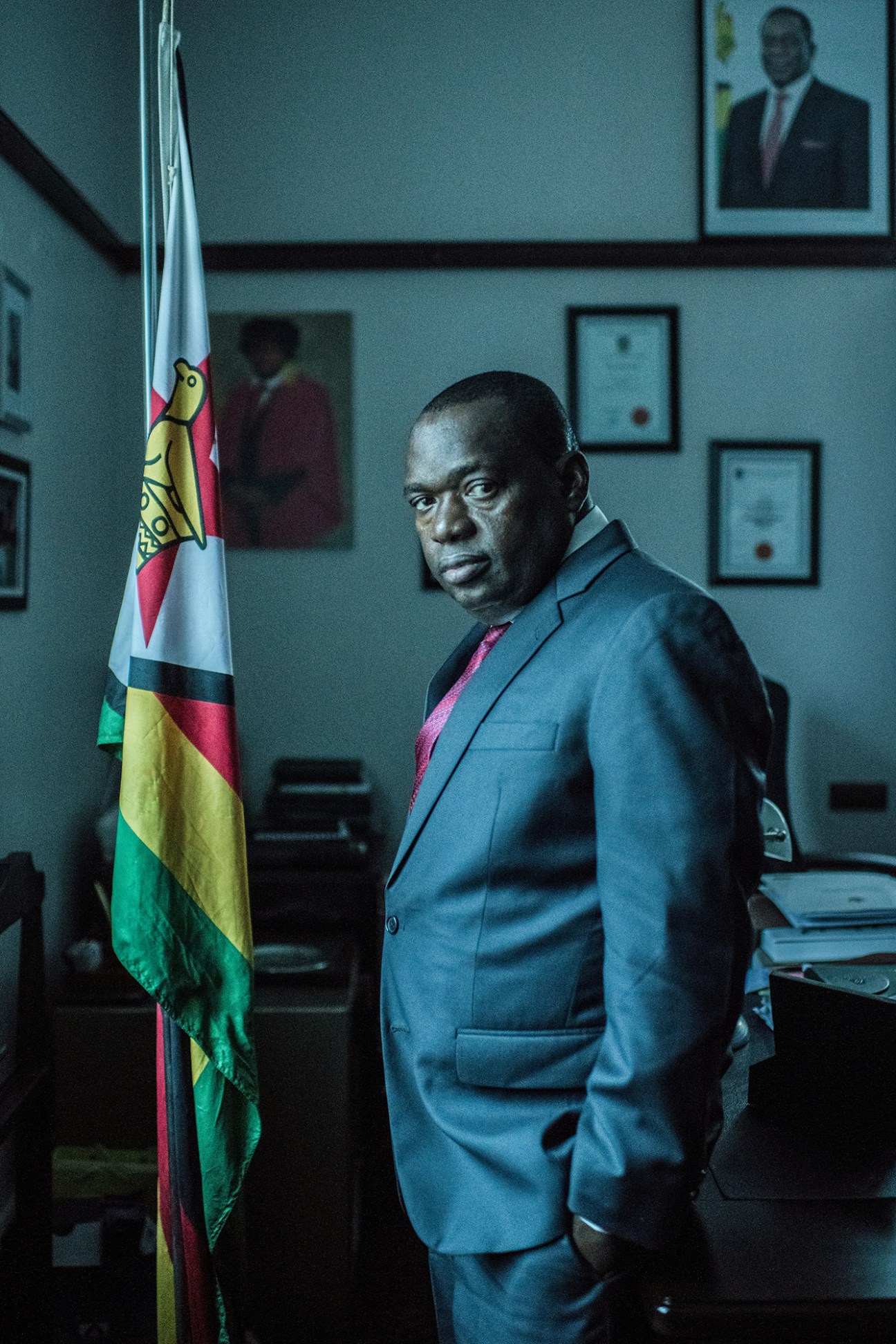 SB Moyo, Zimbabwe's minister of foreign affairs, stands in his office next to the national flag.