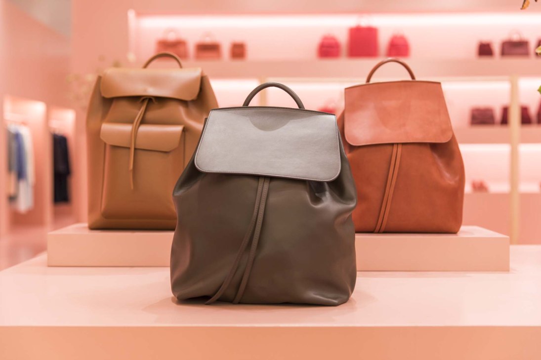 Mansur Gavriel men's calf-leather backpacks displayed on pink shelves in the brand's Soho store.