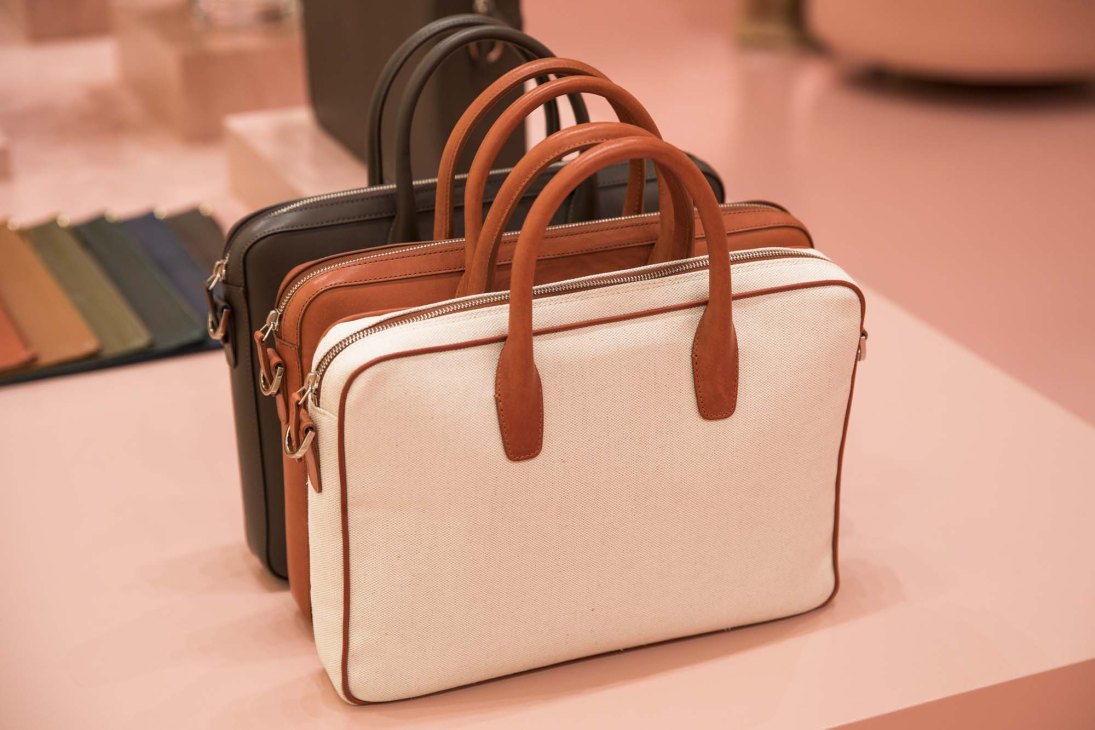 Three Mansur Gavriel leather briefcases in black, cognac, and cream displayed in a row.