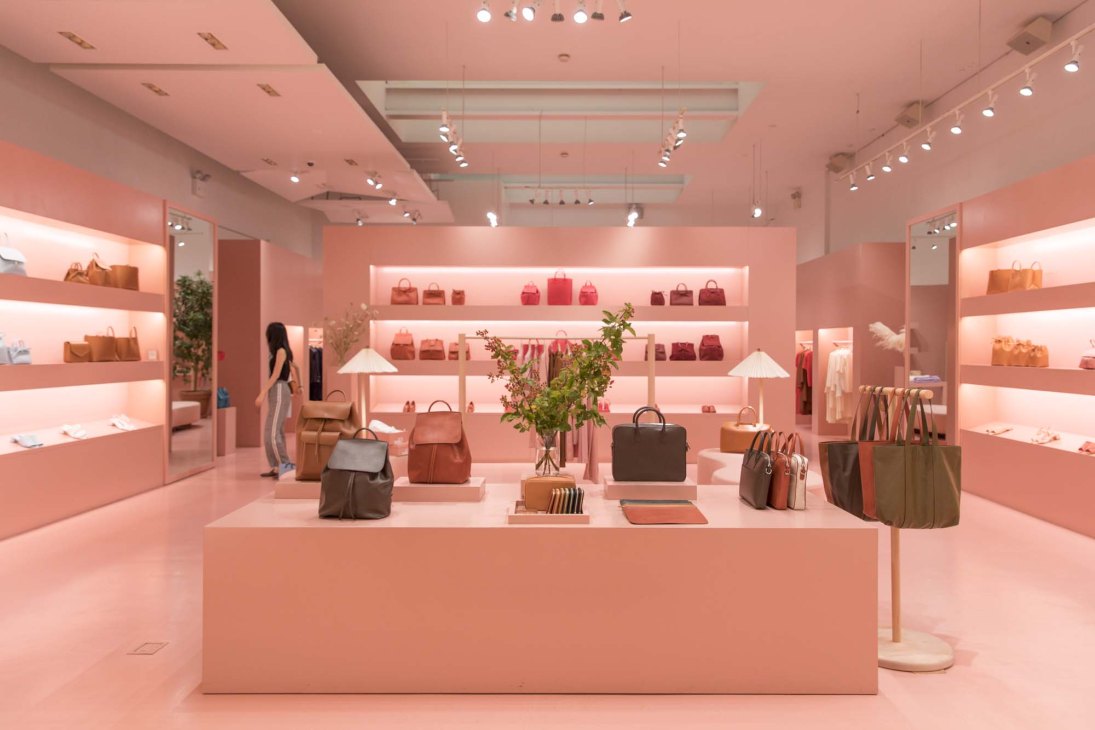 Pink interior of Mansur Gavriel's Wooster Street shop with illuminated shelves displaying leather bags and merchandise.