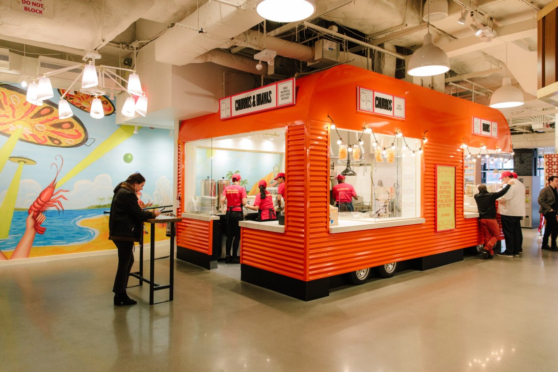 A bright red food stall serving churros at Mercado Little Spain in Hudson Yards.