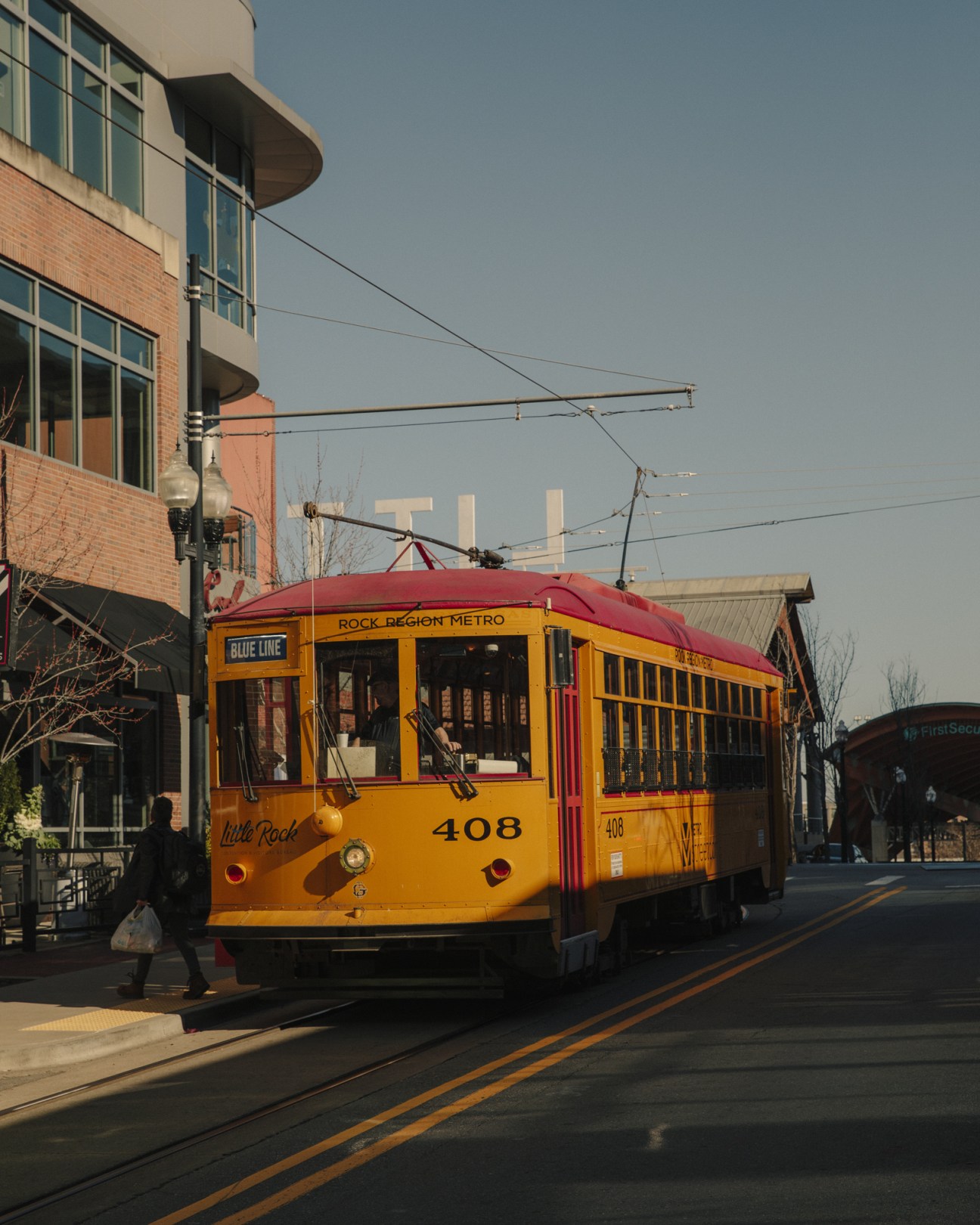 Yellow and red Metro Streetcar numbered 408 traveling through River Market in Little Rock.