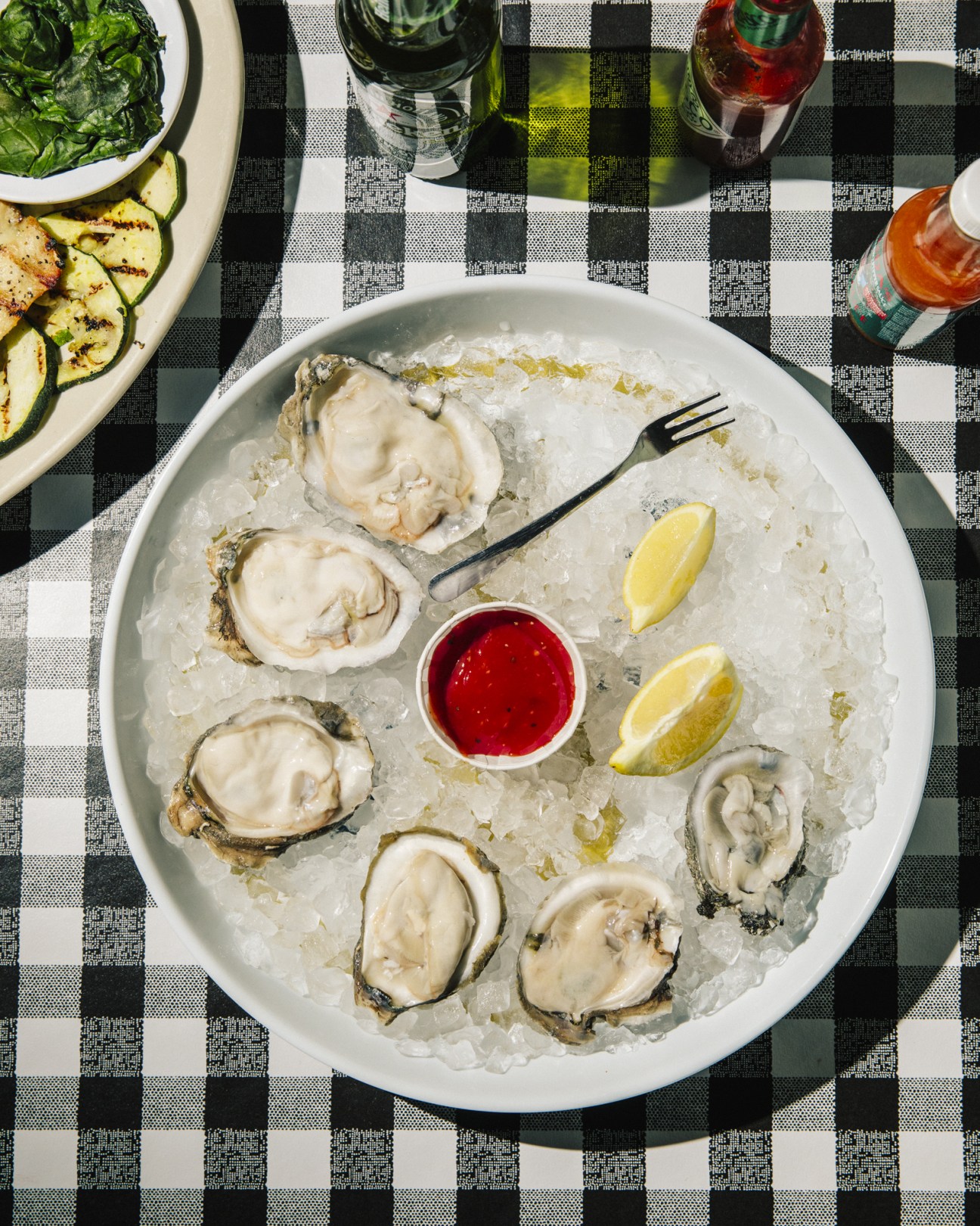Oyster platter served on ice with lemon wedges and red sauce at The Flying Fish restaurant.