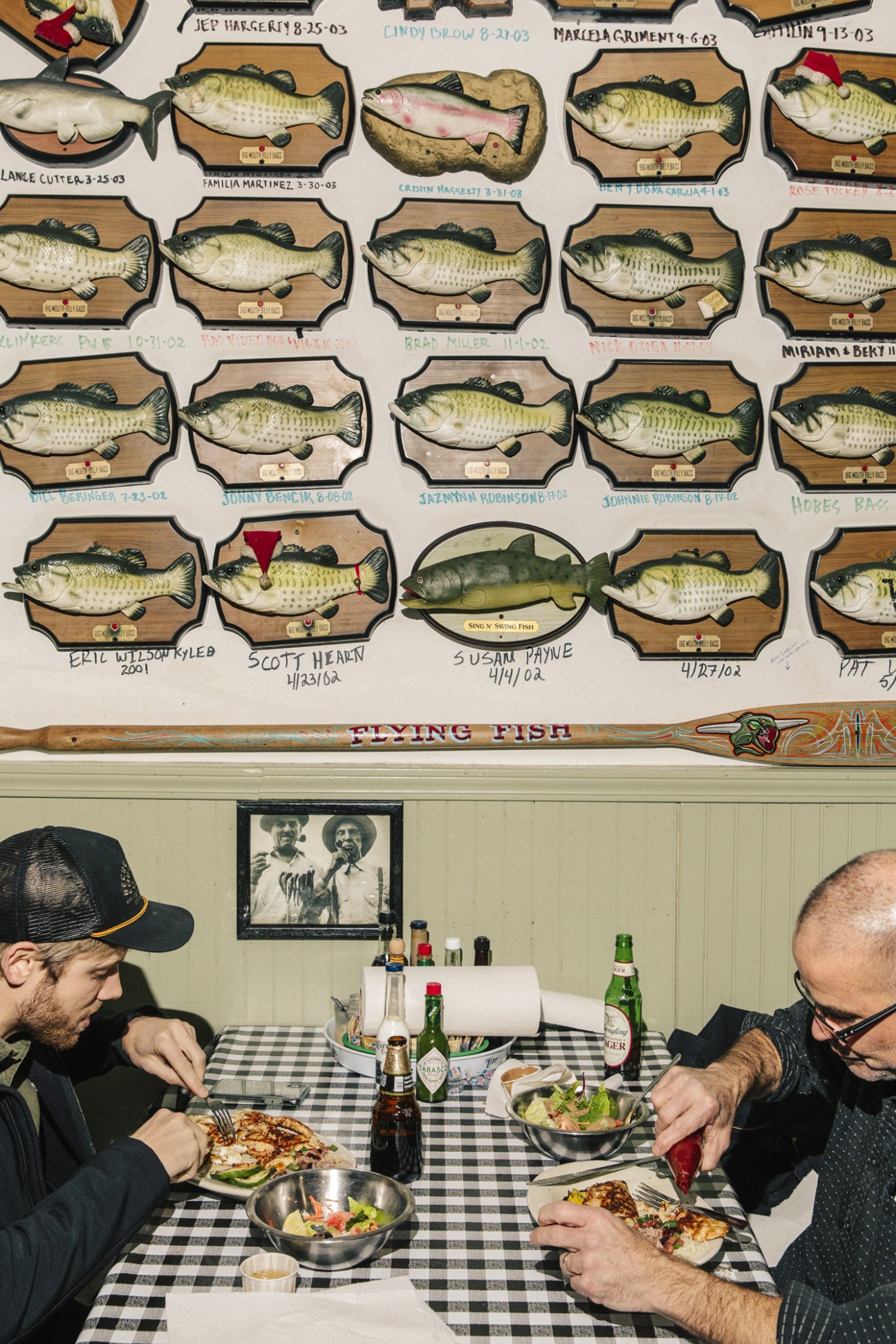 Two diners eat at a table beneath mounted fish displays at The Flying Fish restaurant in Little Rock.