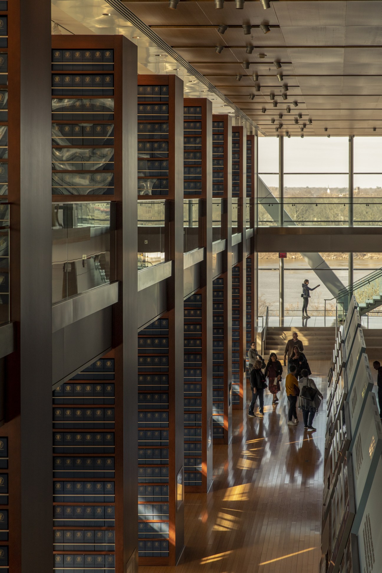 Interior of the William J Clinton Presidential Library with tall display cases and visitors walking through.