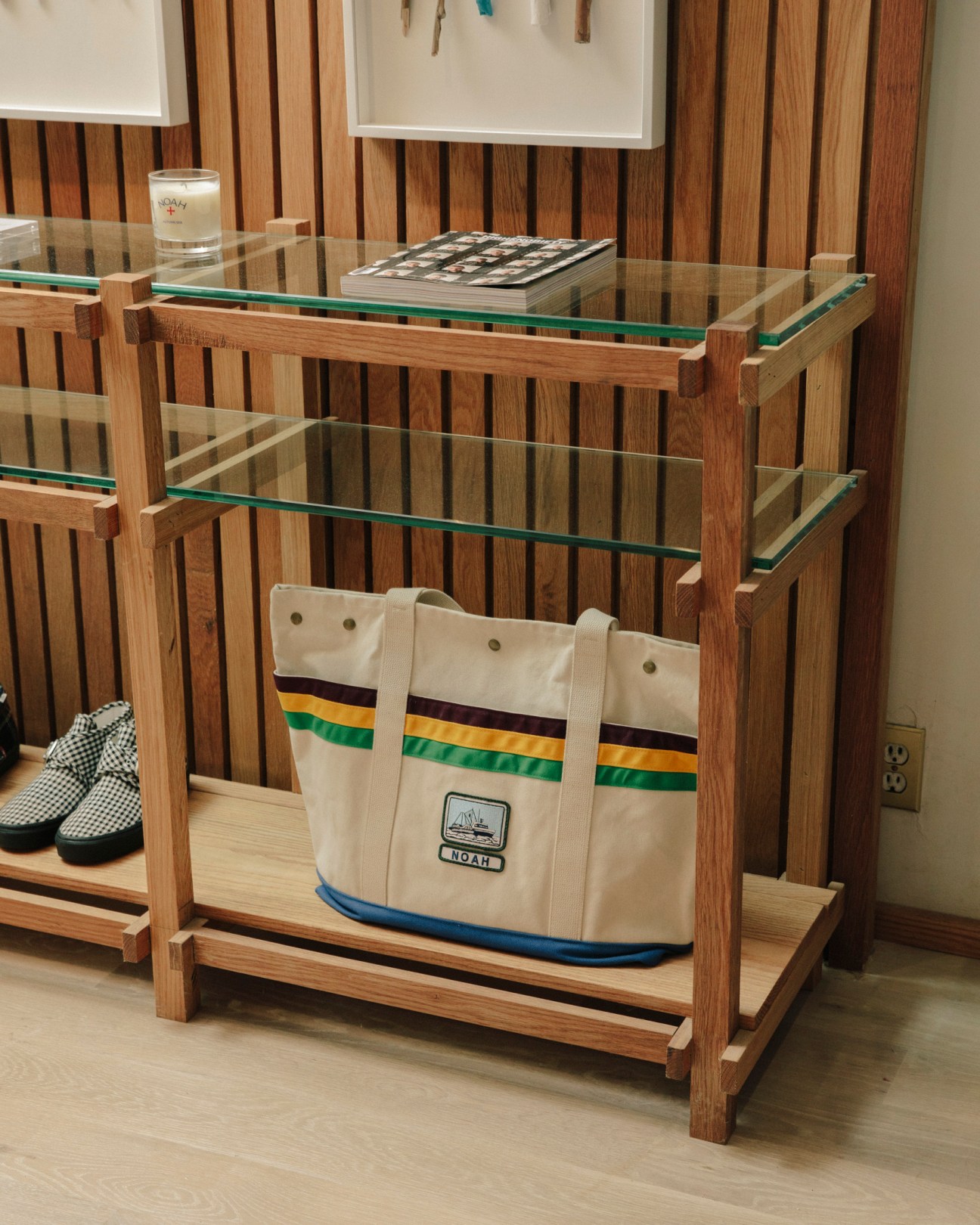 Noah canvas tote bag with green, gold and navy striped trim displayed on wooden retail shelf.