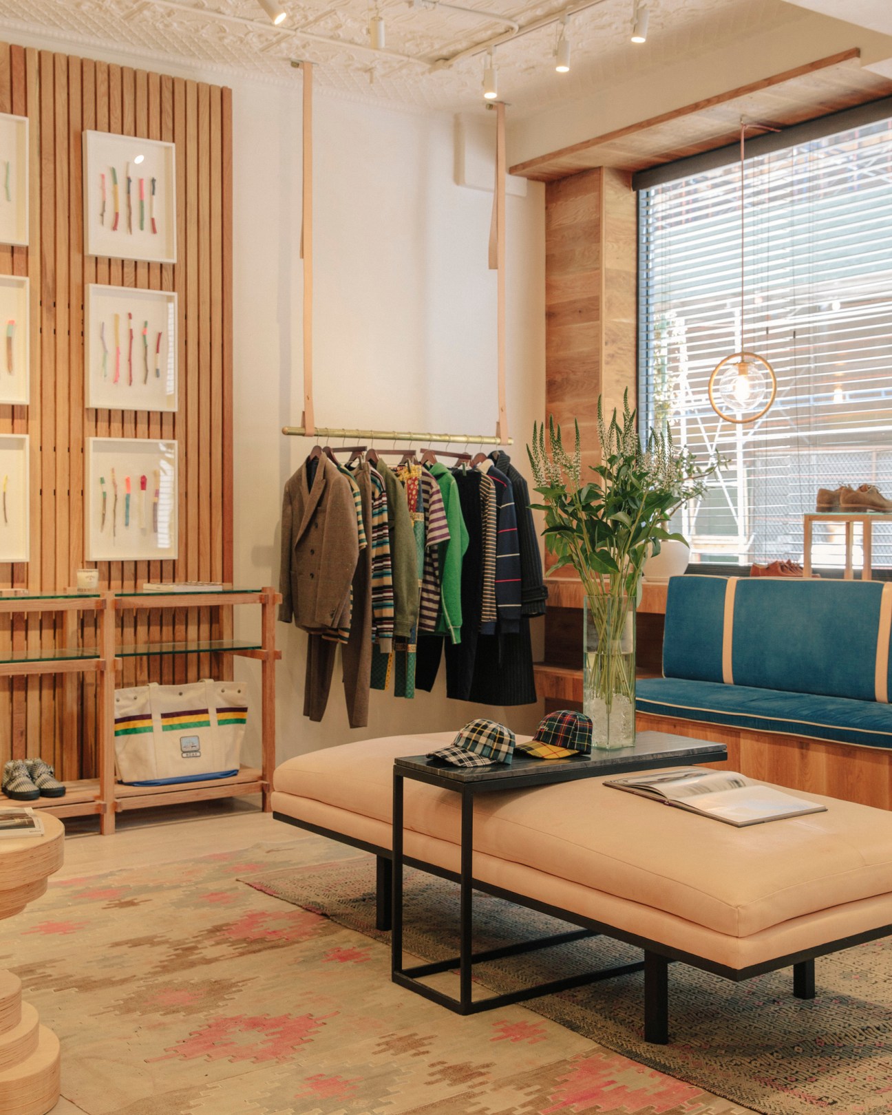 Noah shop extension interior with wooden slat wall, clothing rack, seating area and natural light from windows.