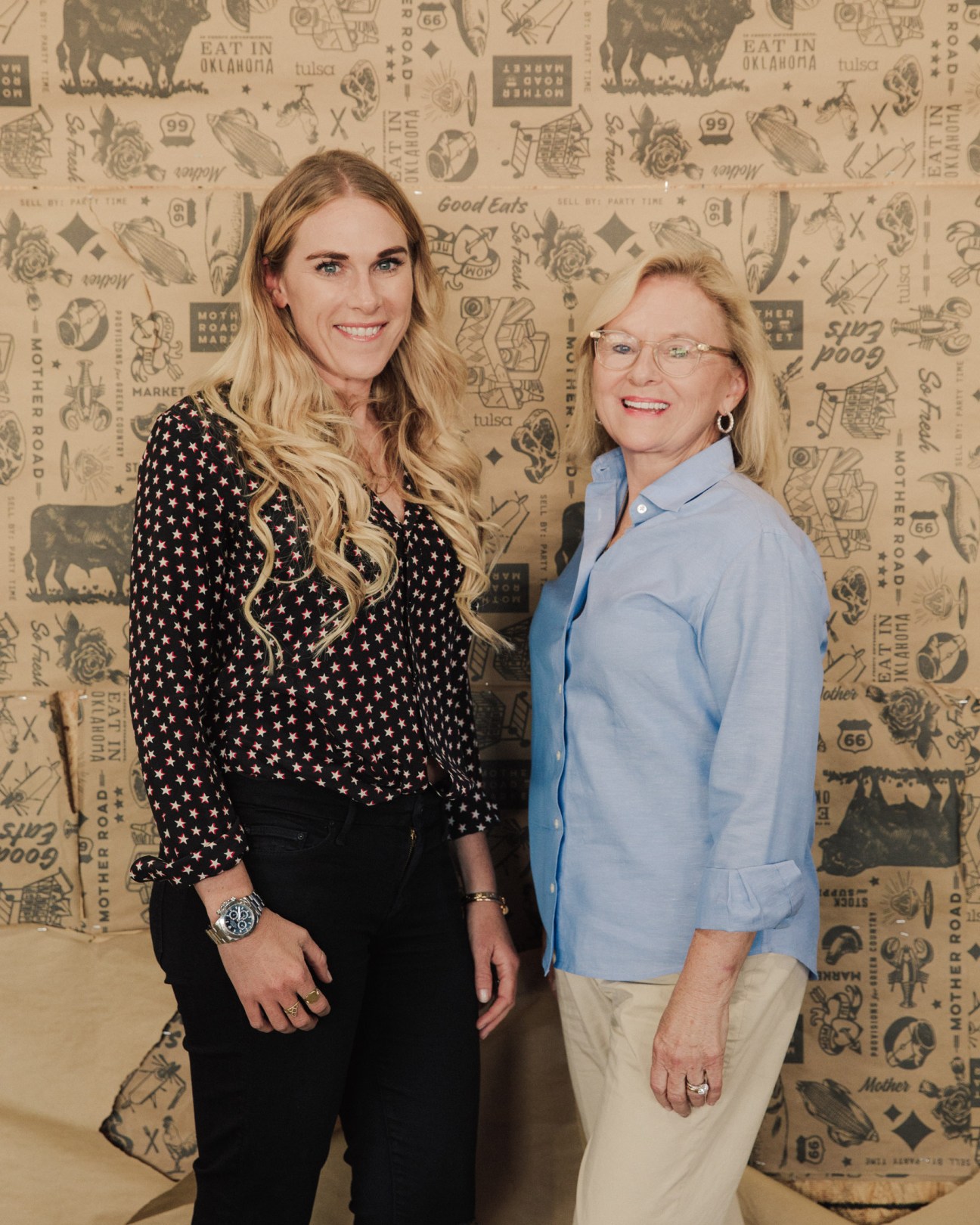 Former mayor Kathy Taylor and daughter Elizabeth Frame Ellison stand together smiling against a patterned backdrop.