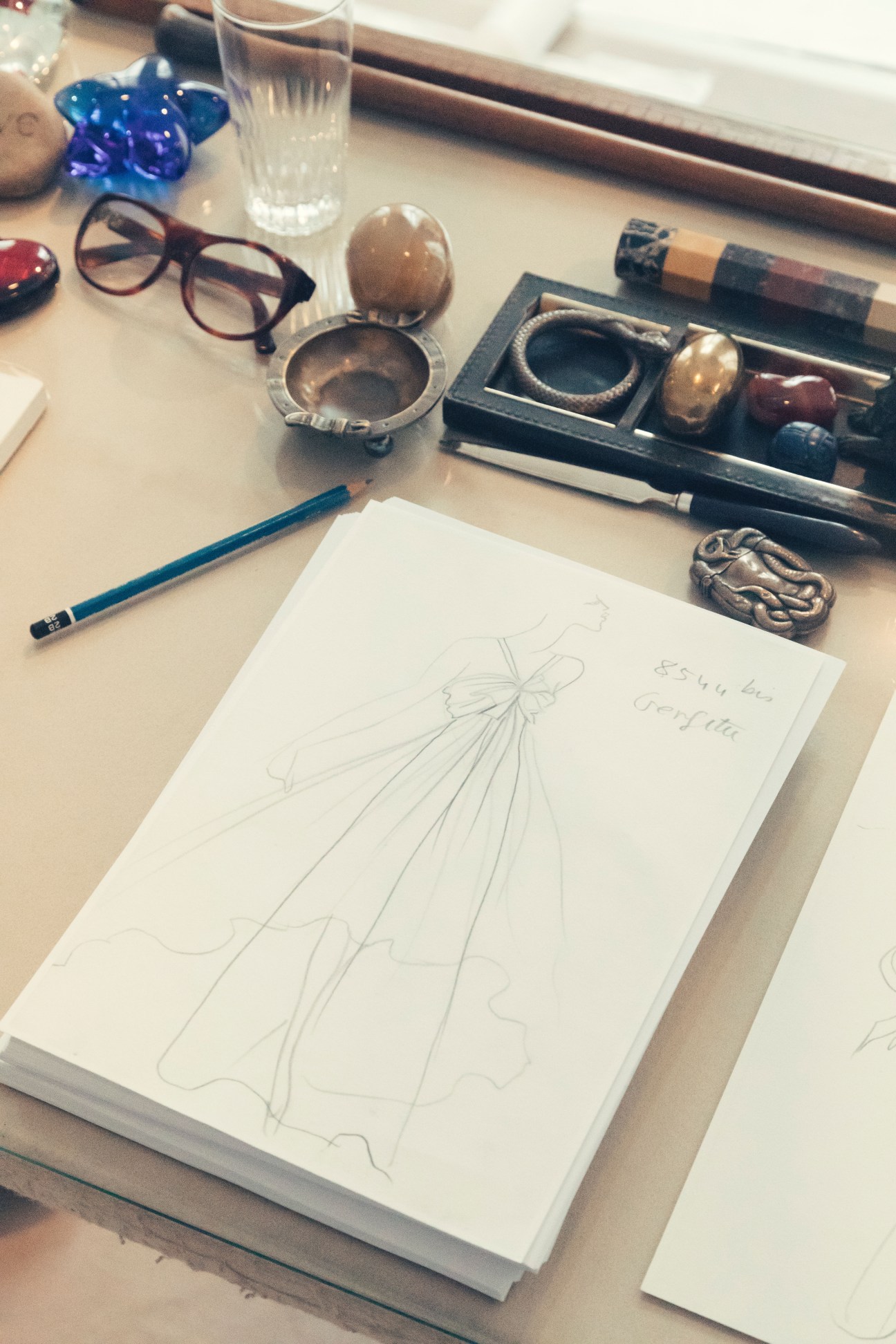 Yves Saint Laurent's fashion sketches and design materials on a work surface.