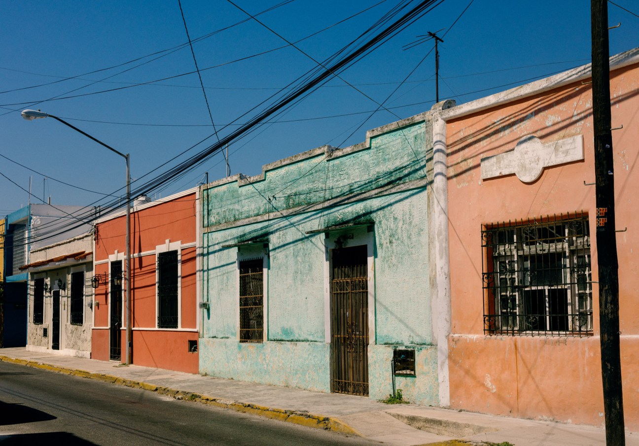 Colourful colonial buildings with orange and green facades in Mérida's Santa Lucía neighbourhood.