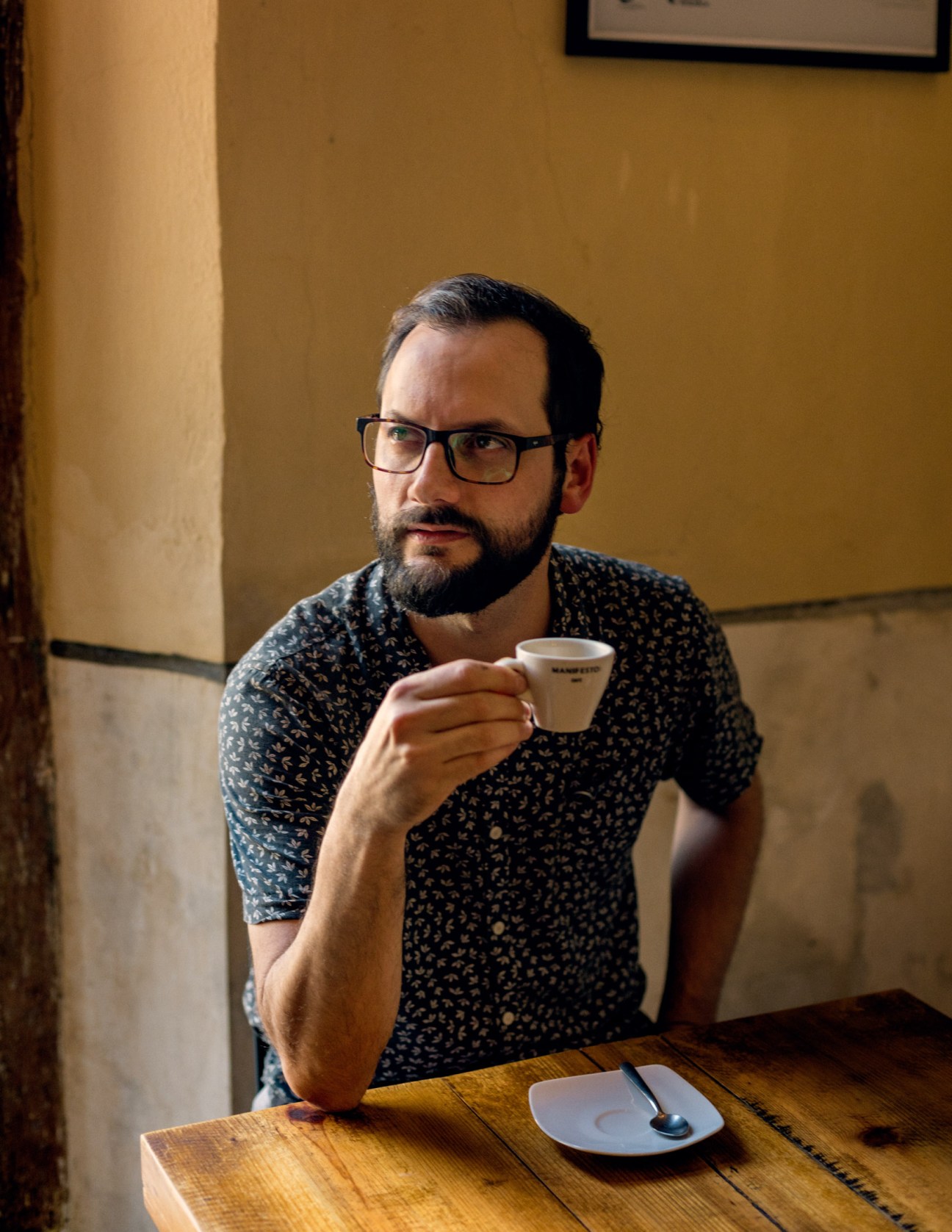 Venezuelan architect Santiago Lazo holding a coffee cup while seated at a table in Manifesto Café.