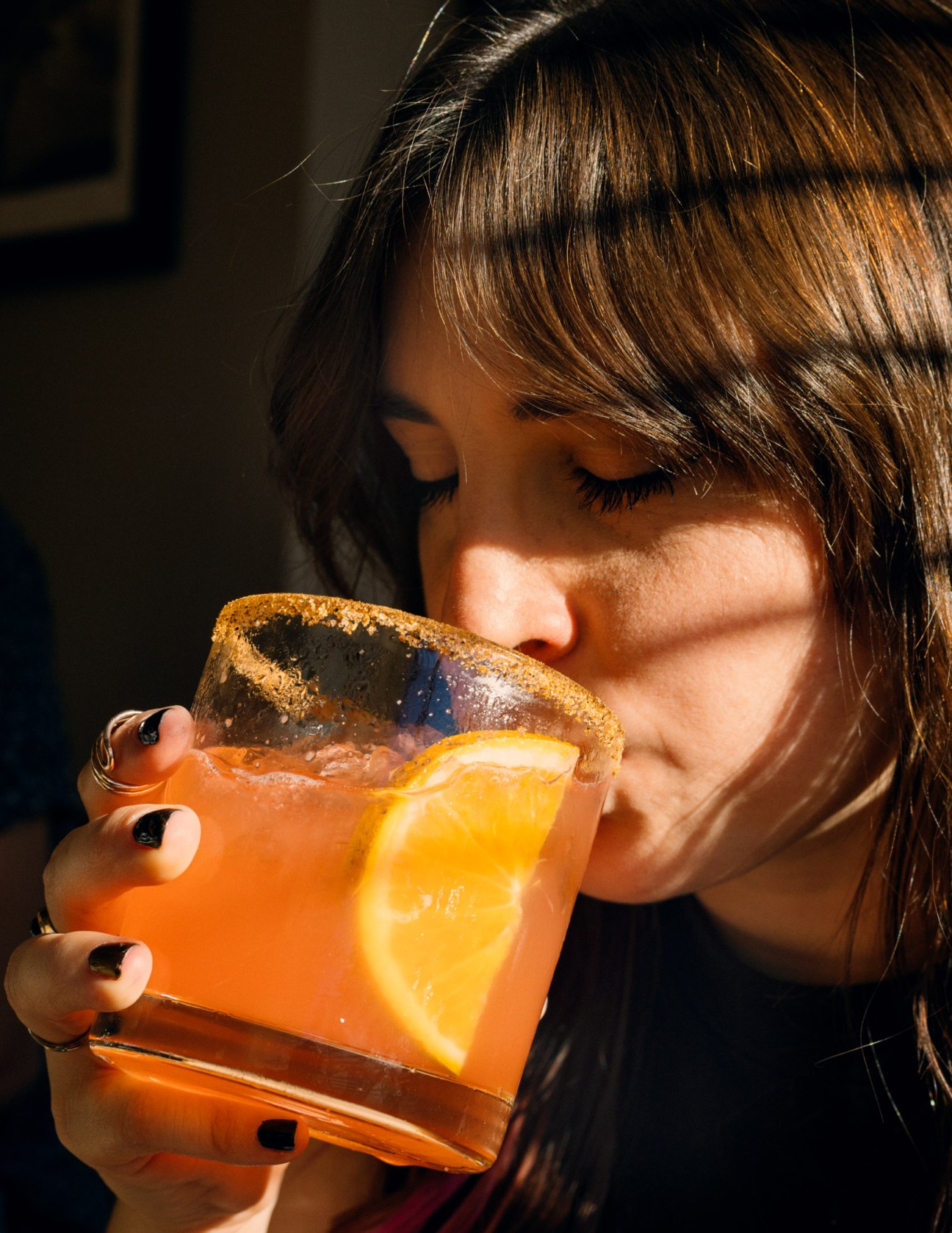 Woman drinking an orange cocktail with an orange slice garnish at restaurant Oliva in Mérida.
