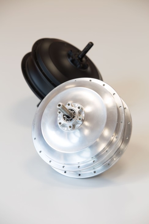 A silver and black rear-hub motor component with mounting bolts, designed for electric bikes.