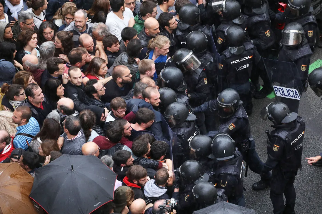 Spanish police in riot gear face off against a large crowd of demonstrators outside a polling station in Barcelona during the 2017 Catalan independence referendum.