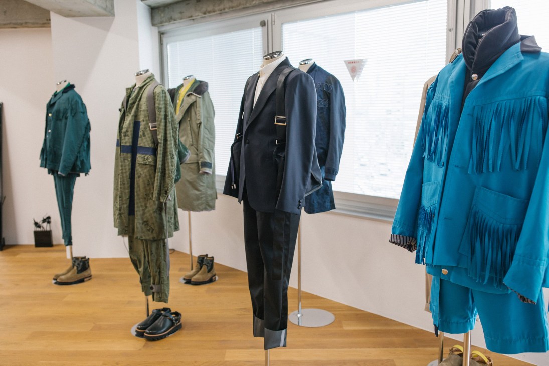 Mannequins display Sacai's spring/summer 2018 menswear collection including patterned jackets and trousers in a bright studio space.