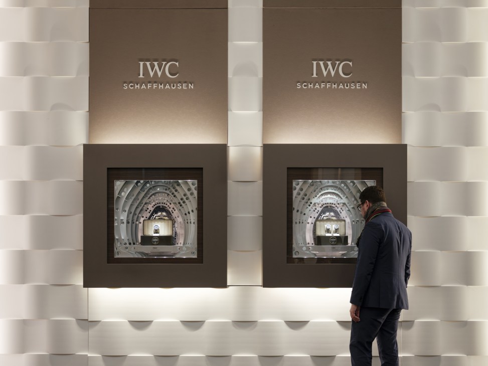 A man viewing IWC Schaffhausen's retail display with illuminated watch showcases at SIHH.
