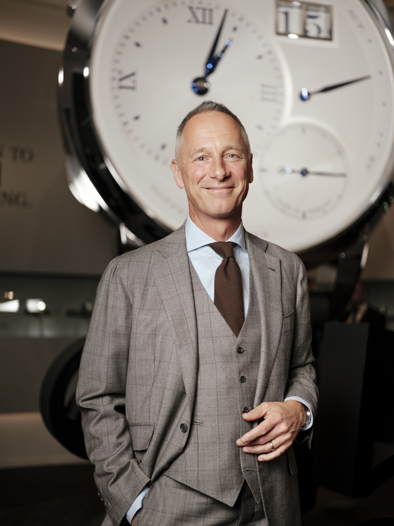 Wilhelm Schmid, CEO of A Lange & Söhne, standing in front of a large white watch face.