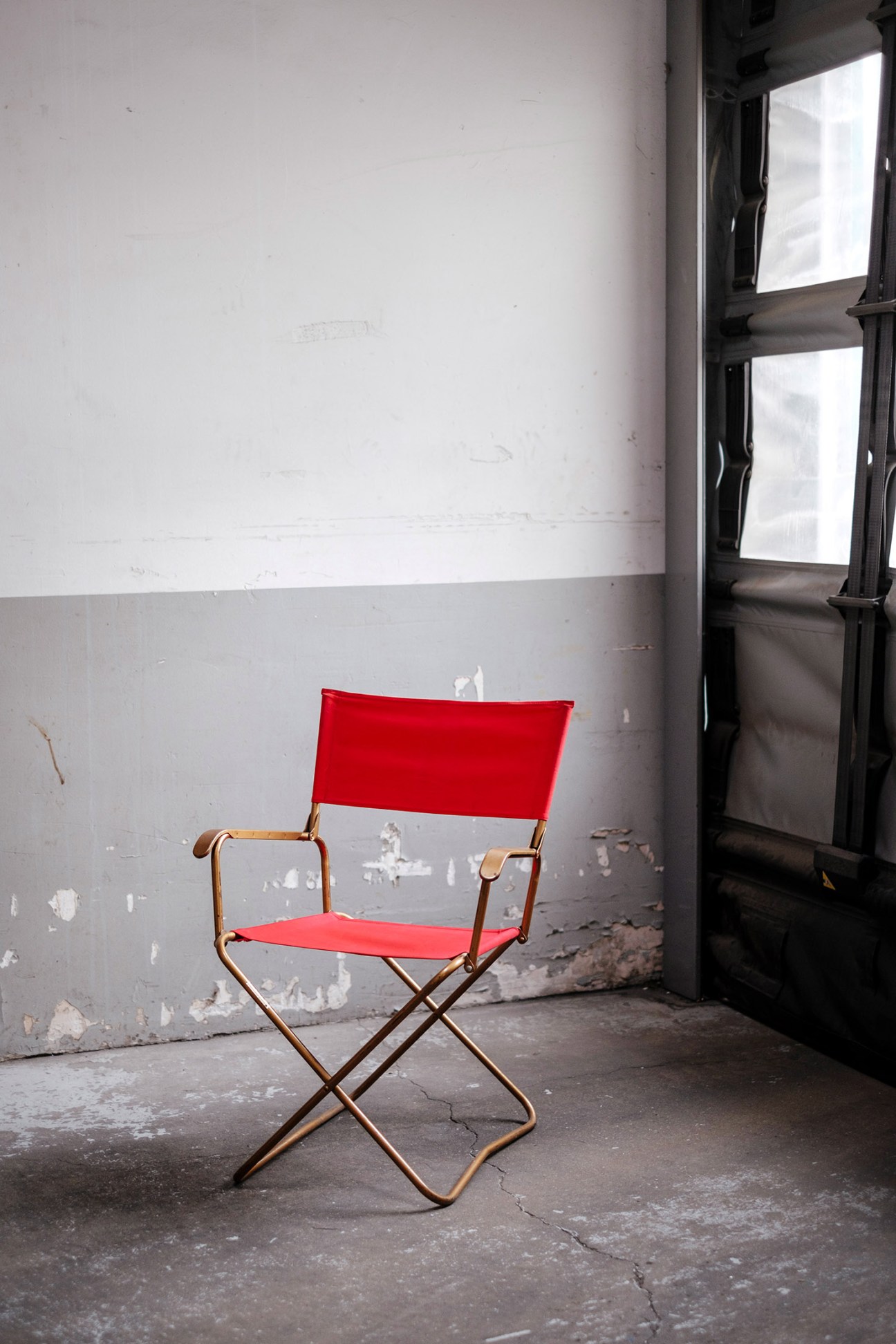 Red fabric folding camping chair with metal frame in an industrial warehouse space