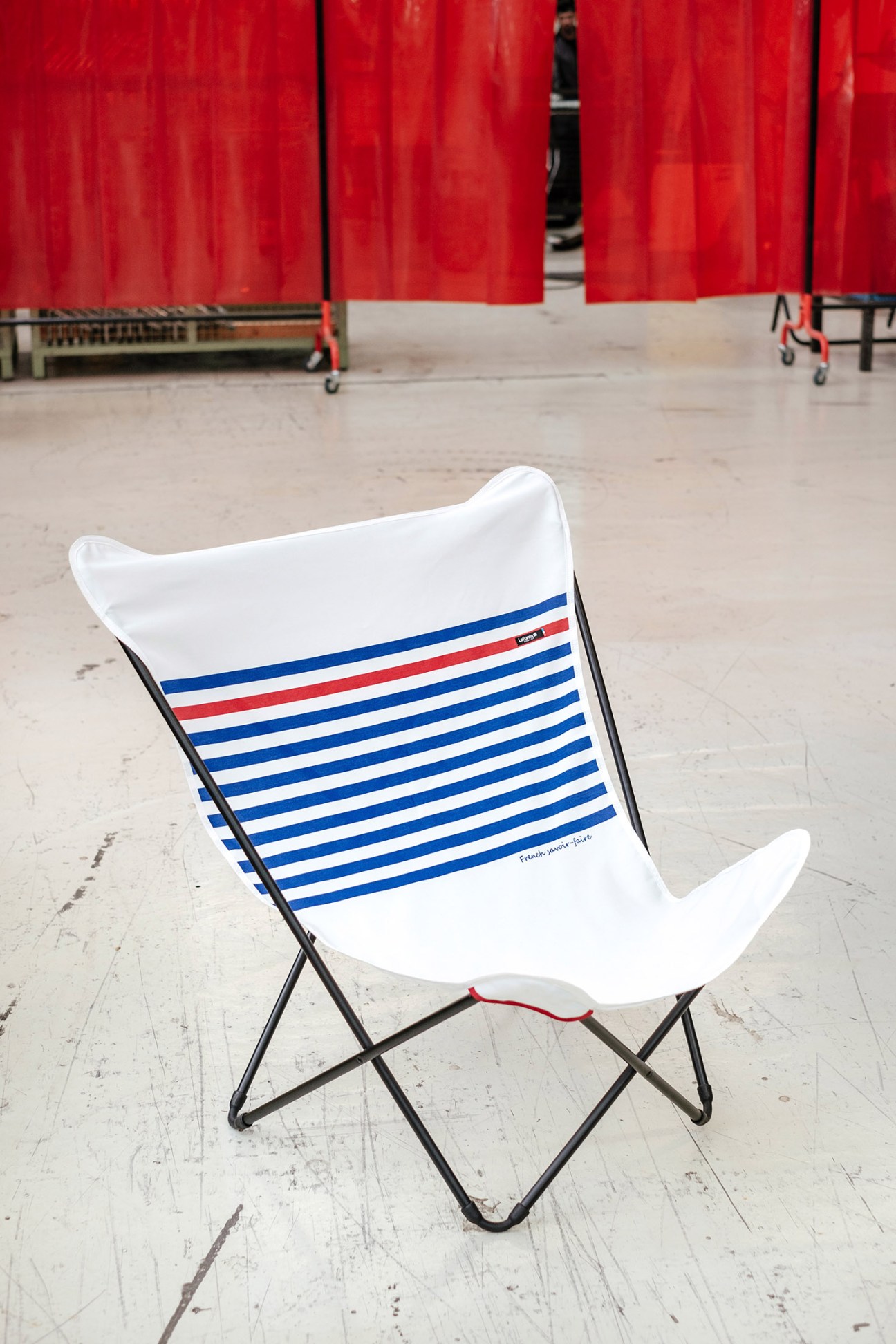 Lafuma Mobilier's Pop Up chair in white with blue and red stripes on concrete ground.