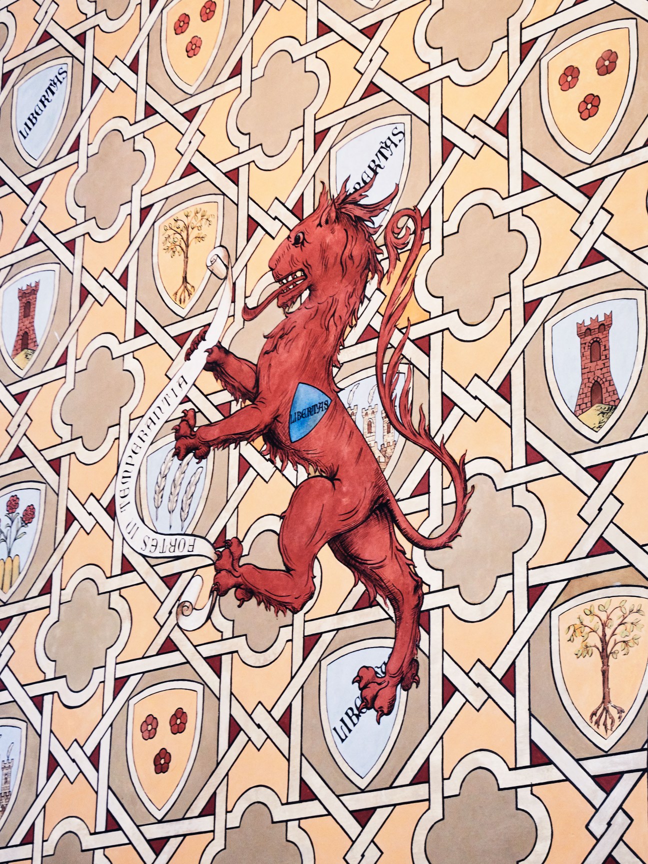 Illustration of a red lion rearing up surrounded by heraldic shields featuring San Marino symbols including towers, flowers, and text.