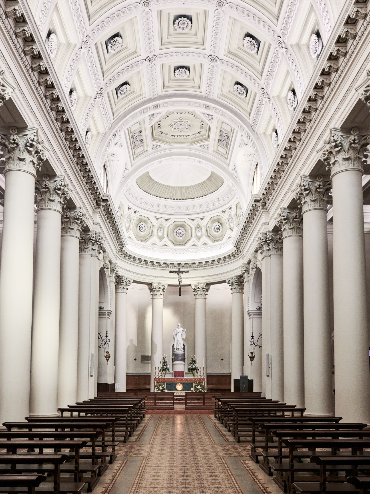 Interior of Basilica di San Marino with ornate white ceiling, Corinthian columns and central altar.