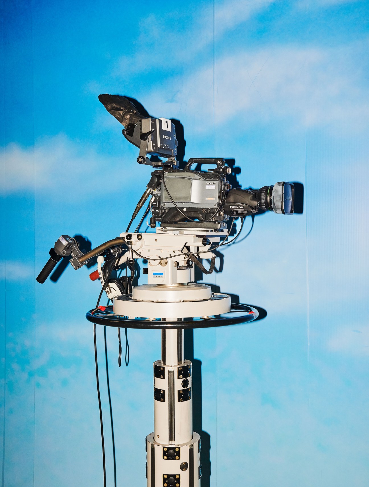Professional television camera mounted on a rotating platform against a blue sky.