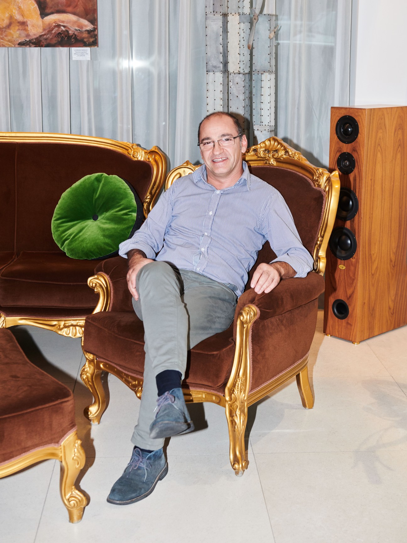 Hotel proprietor Francesco Brigante sits in an ornate gold-framed brown velvet chair.